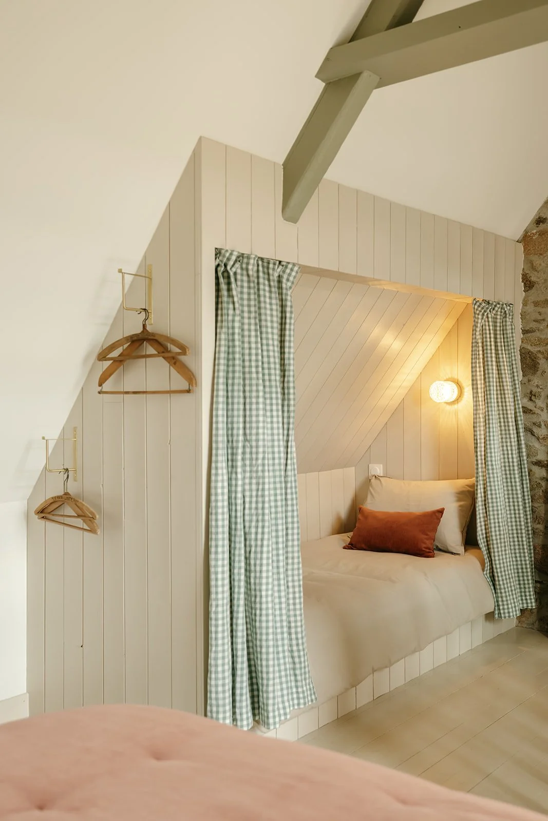 Aménagement sous pente en bois sur mesure avec espace nuit intégré, lit et rideaux