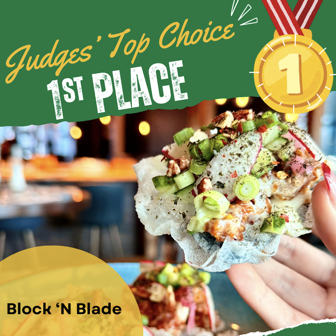 A hand holding a crispy taco topped with chopped green onions, diced radishes, nuts, and a creamy sauce, with a blurred restaurant background and a golden medal icon indicating first place.