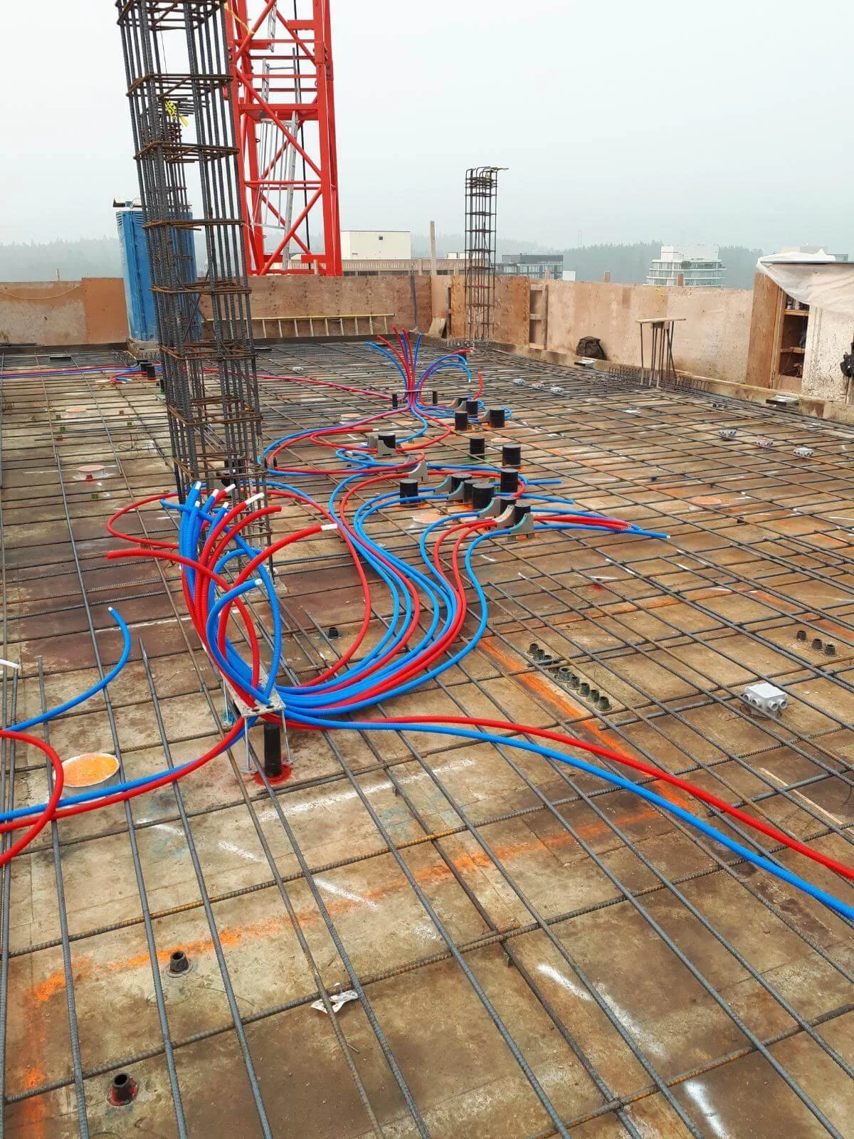 Construction site with exposed rebar and plumbing pipes on a building floor under construction.