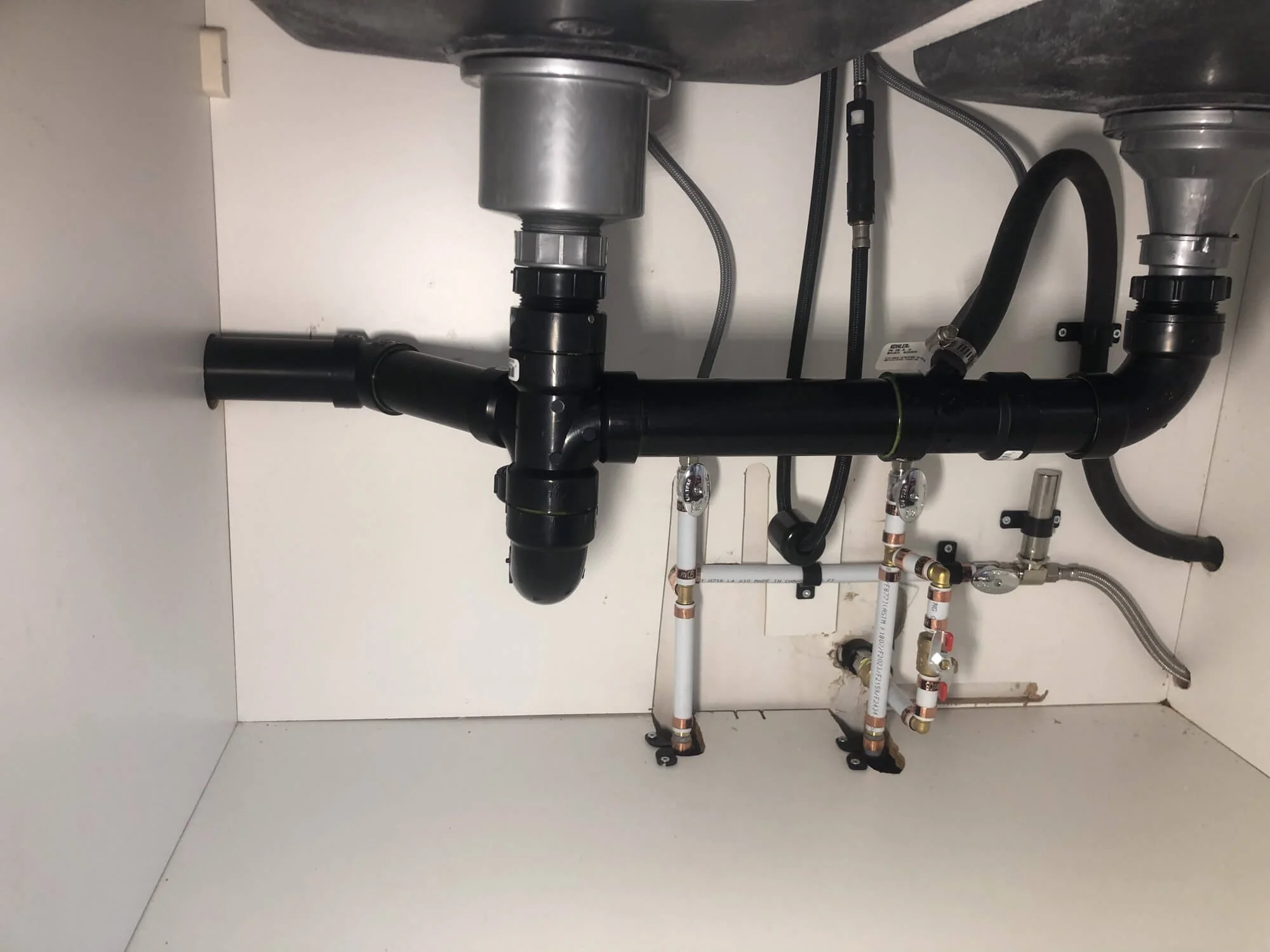 Professional under-sink plumbing installation featuring high-quality PVC drainage and copper supply lines in a Vernon home.
