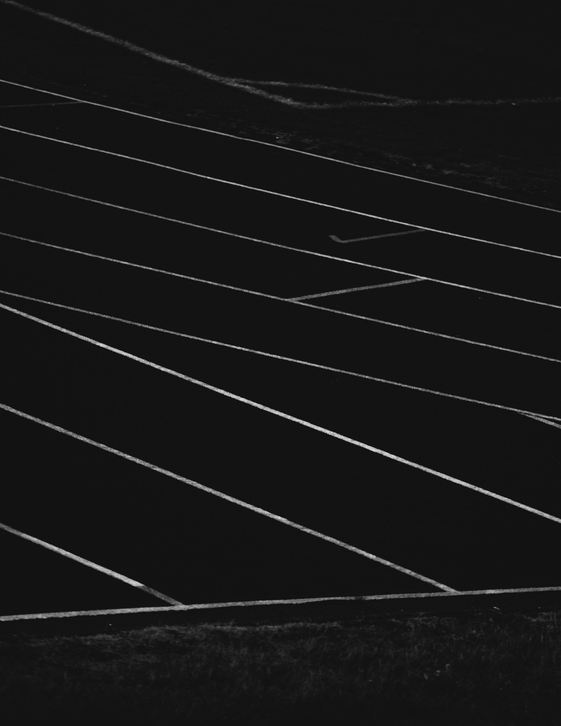 An empty athletic running track with multiple lanes marked by white lines, viewed from an overhead angle.