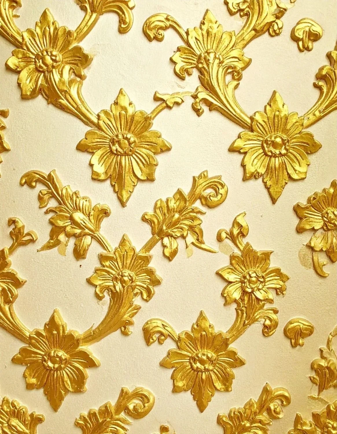 Golden floral pattern with ornate flowers and leaves on a light background.