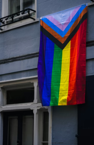 A rainbow pride flag hanging on the side of a building.