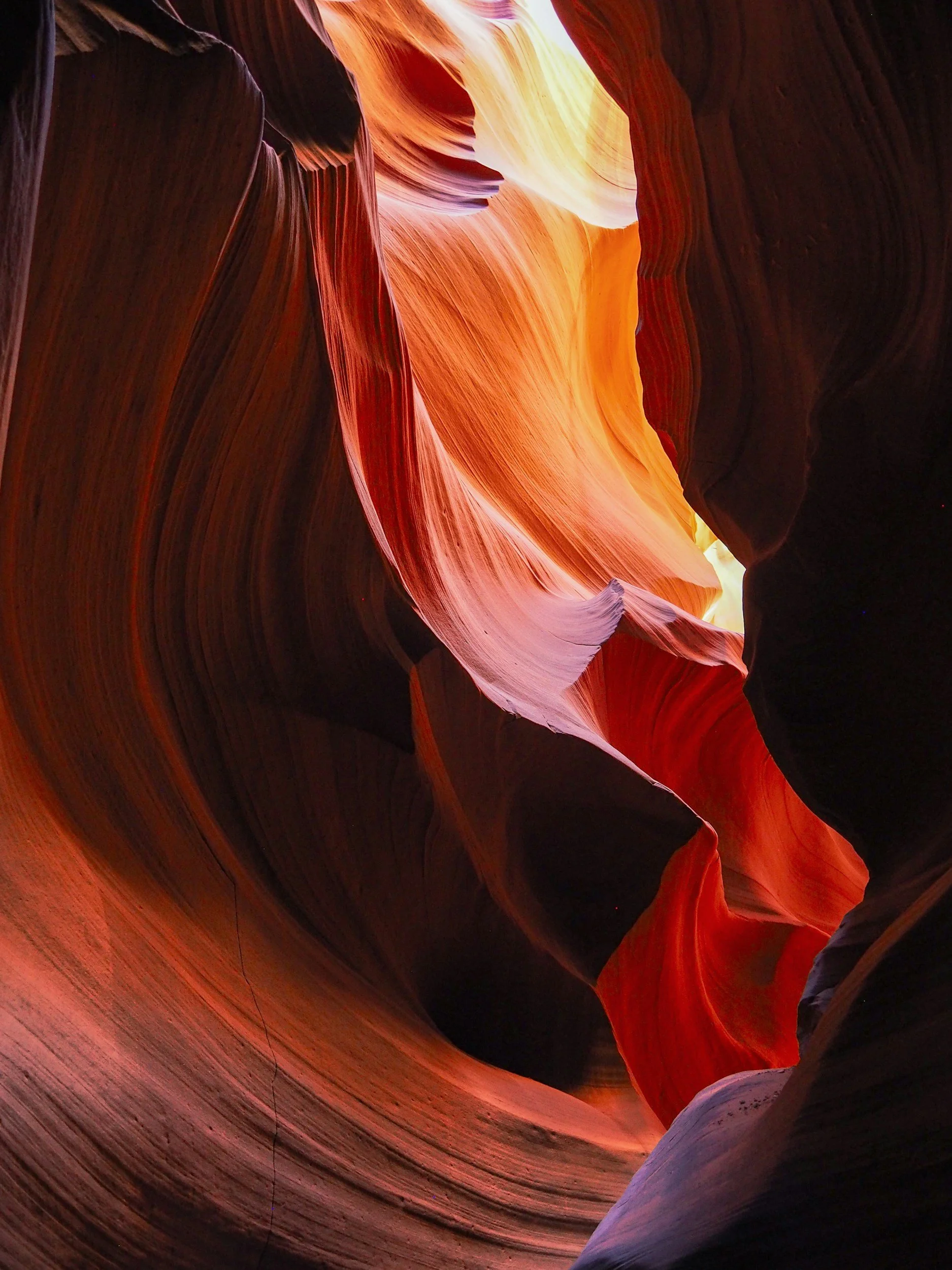 Inside view of a slot canyon with flowing red, orange, and purple rock formations.