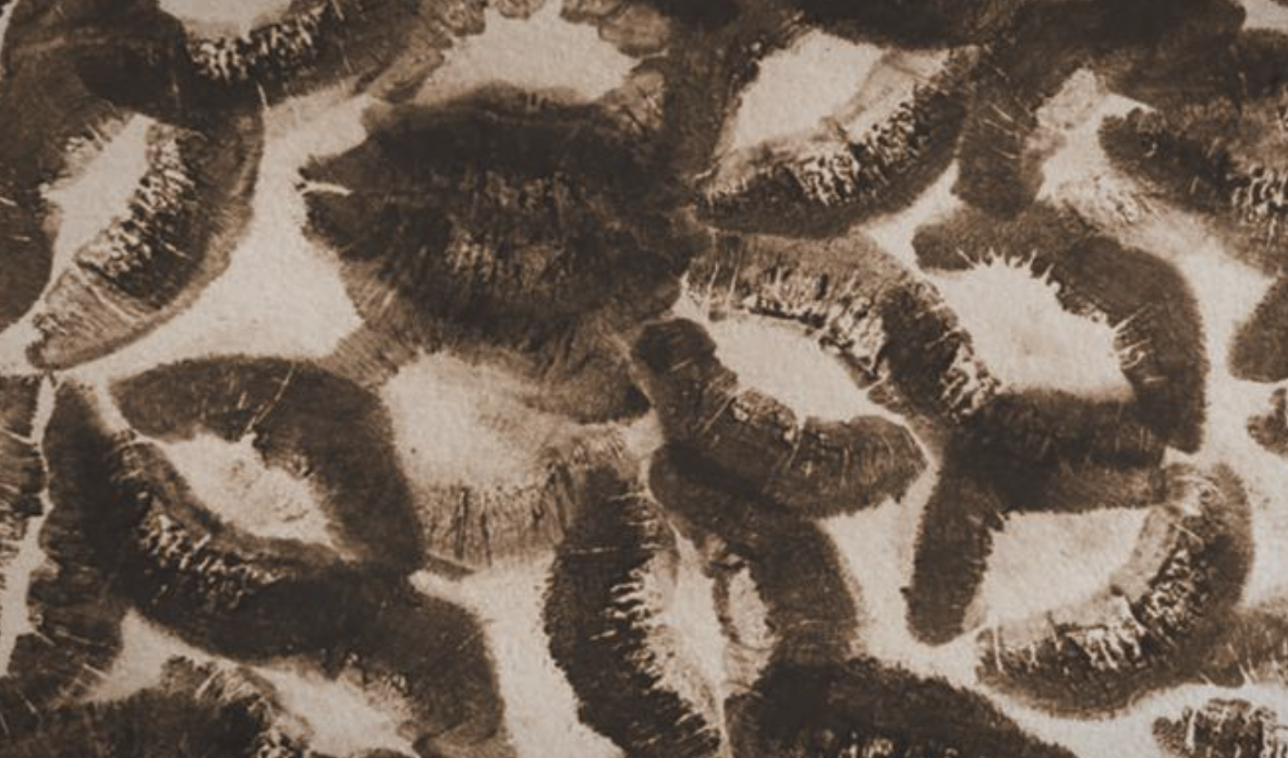 Close-up of numerous lipstick kiss marks on a fabric surface.