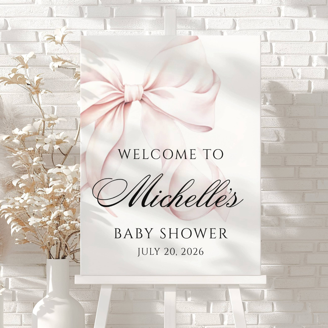Welcome sign for Michelle's baby shower on July 20, 2026, featuring a pink bow design on a white canvas with decorative flowers in a vase beside it.