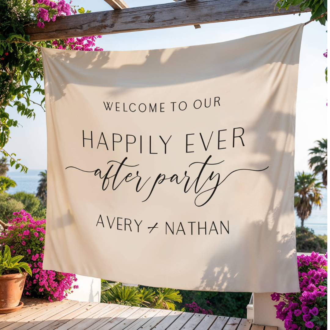 A welcome banner at an outdoor wedding reception reading 'Welcome to our happily ever after party, Avery & Nathan,' hanging from a wooden beam with flowering plants and trees in the background.