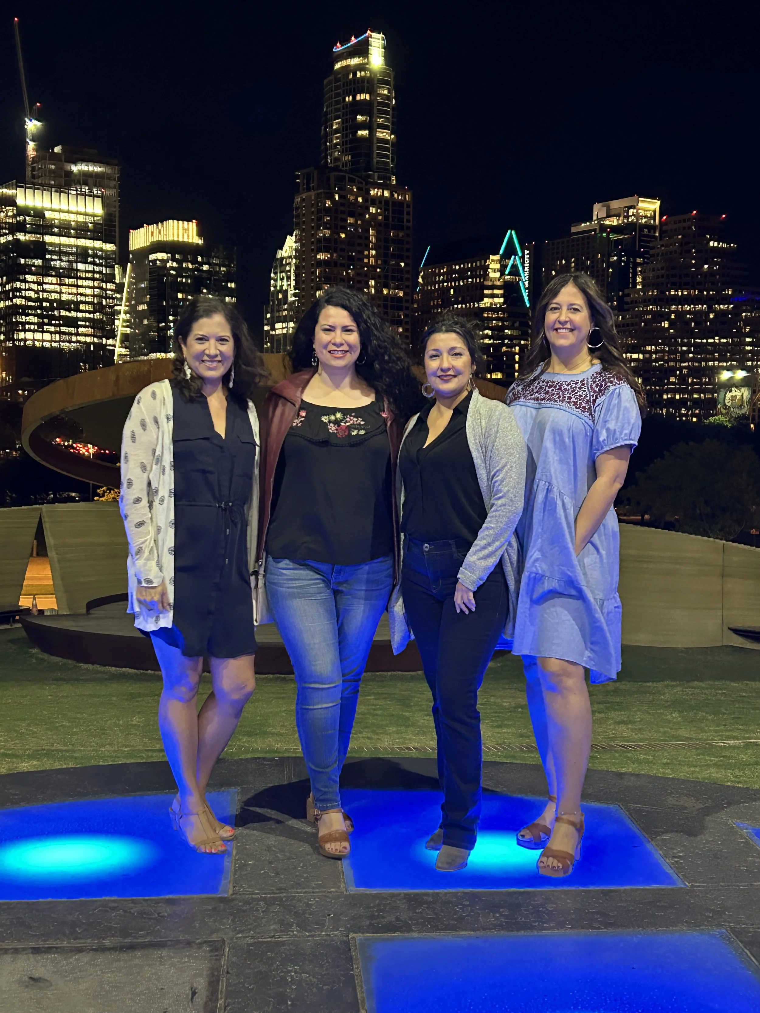 Four bold women taking a picture together in a city night