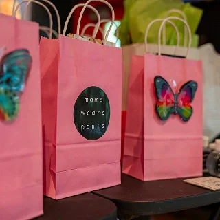 Pink gift bags with butterfly decorations from mama wears pants on display.