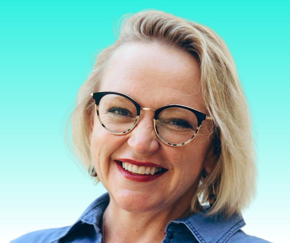 A woman with blonde hair, wearing glasses and a blue shirt, smiling at the camera against a turquoise background.