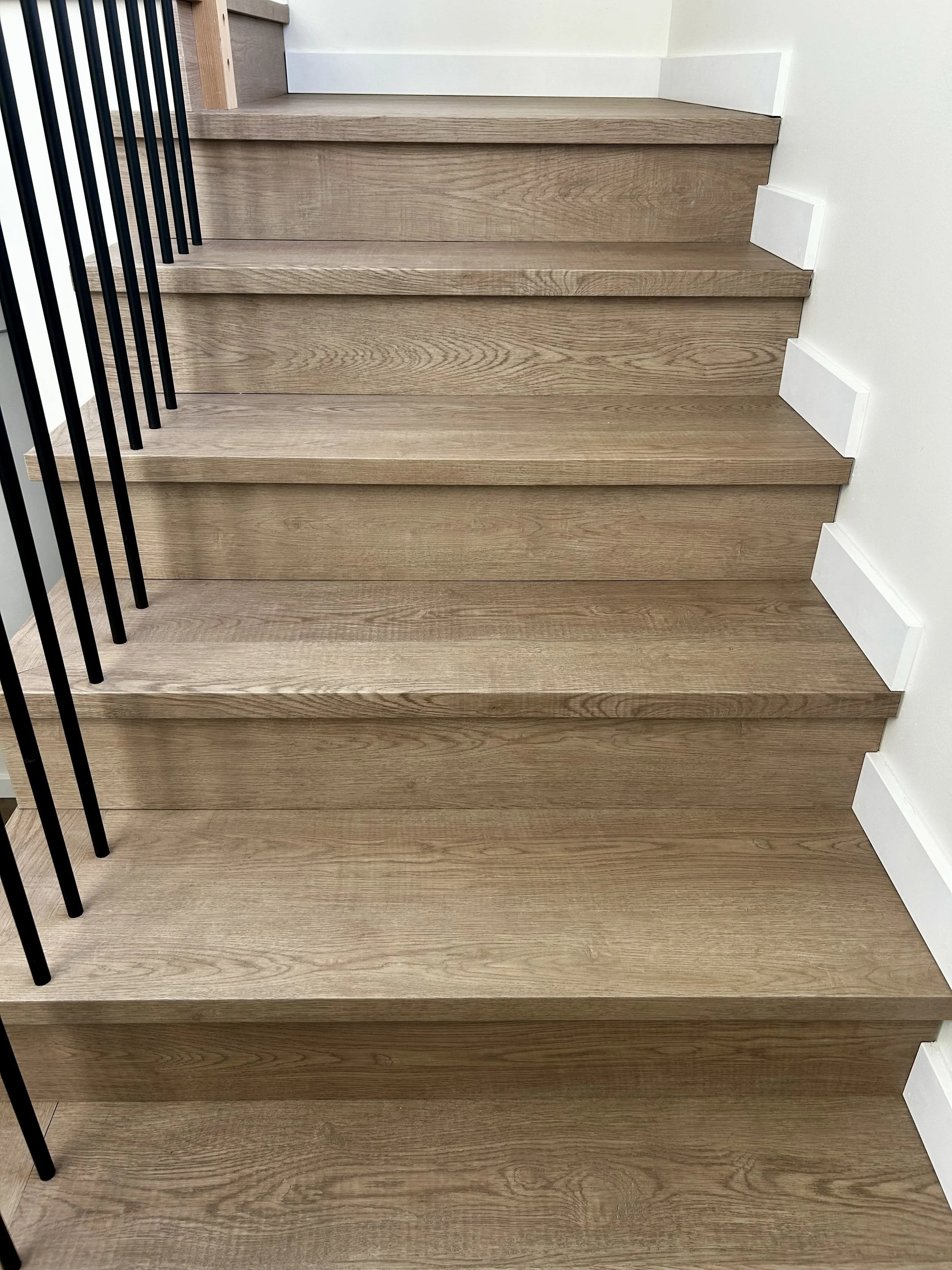 Wooden staircase with white risers and black metal railing.