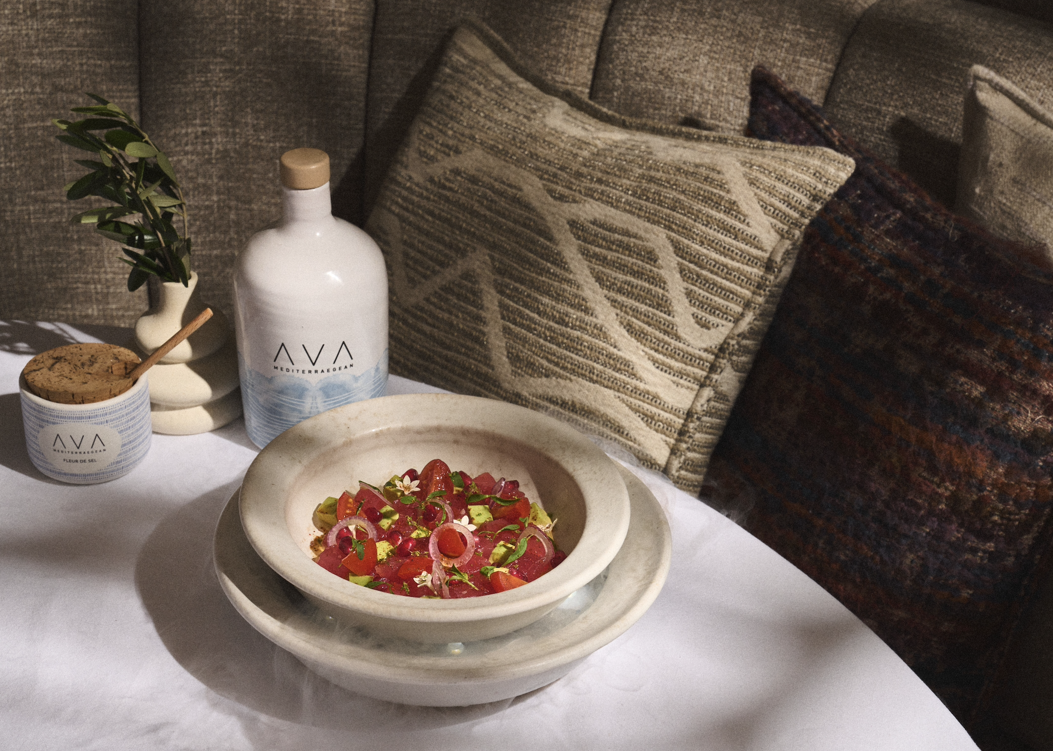 White round table at AVA Coconut Grove with a fresh dish next to a couch and pillows