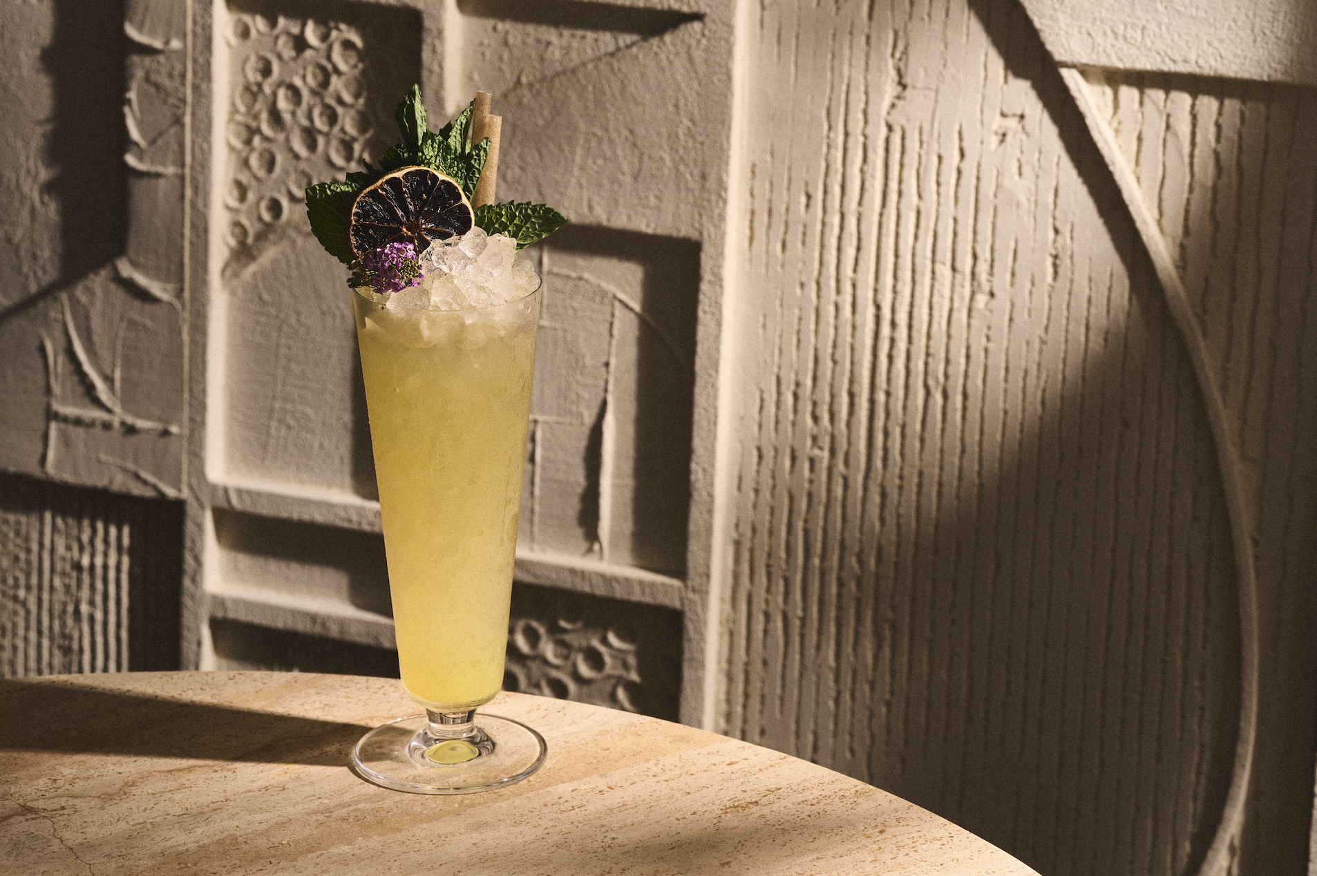 Refreshing yellow cocktail with garnishes on a table at AVA Coconut Grove