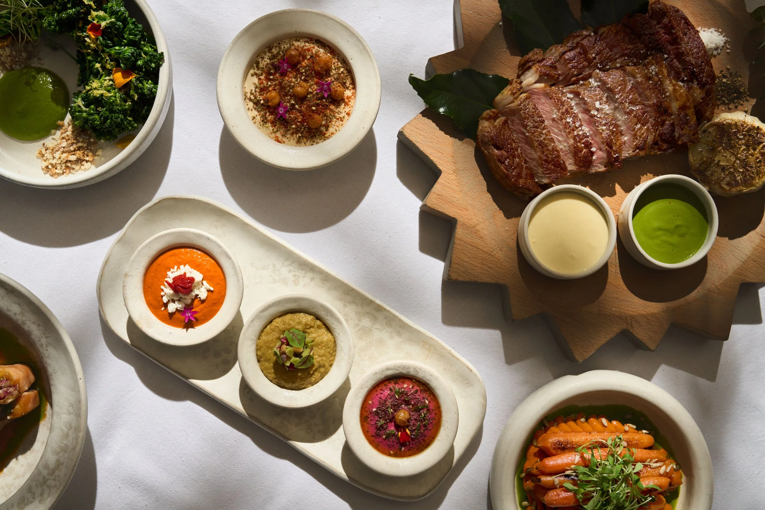 A spread mezze, with a meat dish and some vegetables all served at AVA Coconut Grove