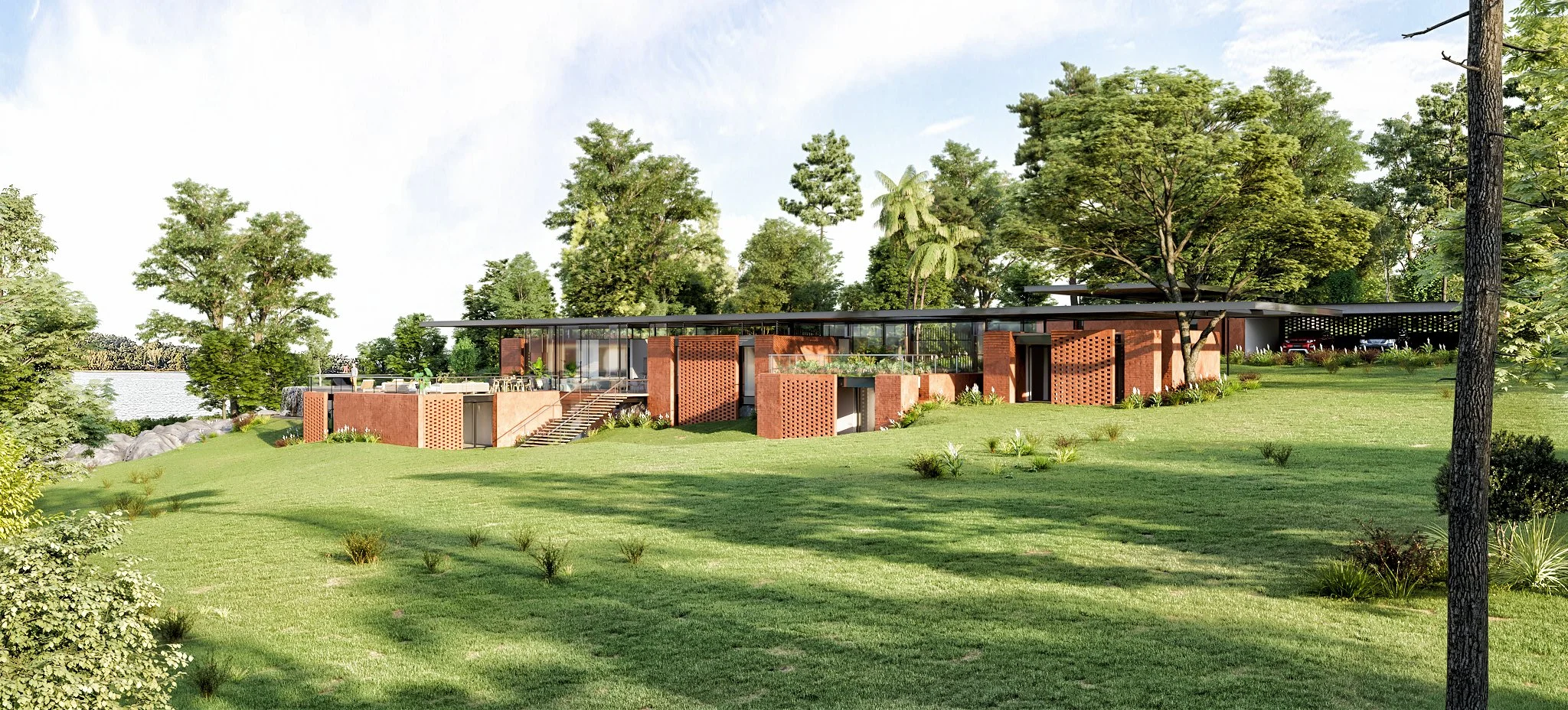 Modern house with large glass windows and brick walls, situated on a grassy lawn with trees and a body of water nearby.