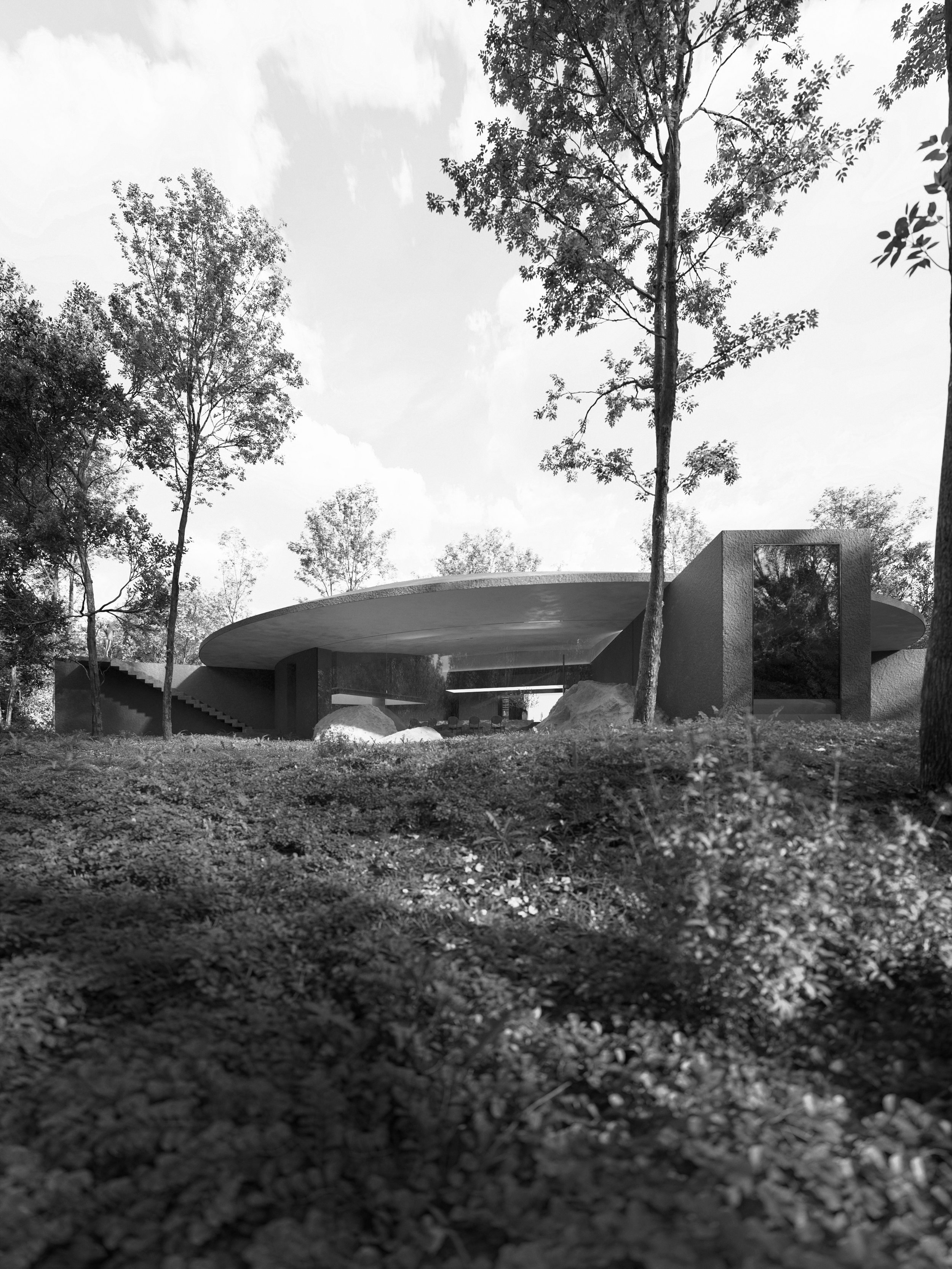 Modern building with a large flat roof, surrounded by trees and natural landscape.