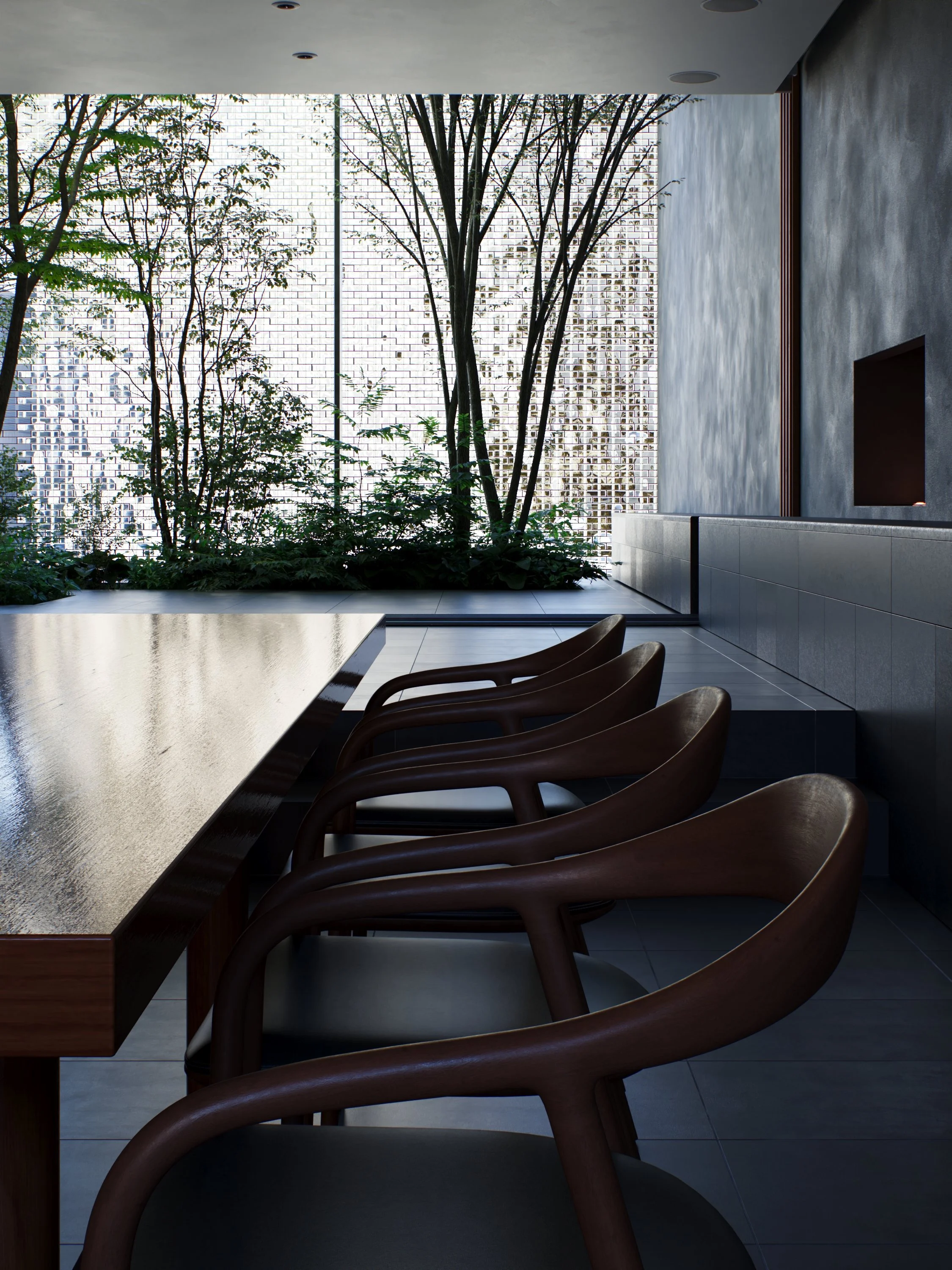 A modern interior space with a long wooden dining table, several wooden chairs with curved backs, a large window with trees outside, a textured gray wall with a built-in niche, and a white tiled floor.