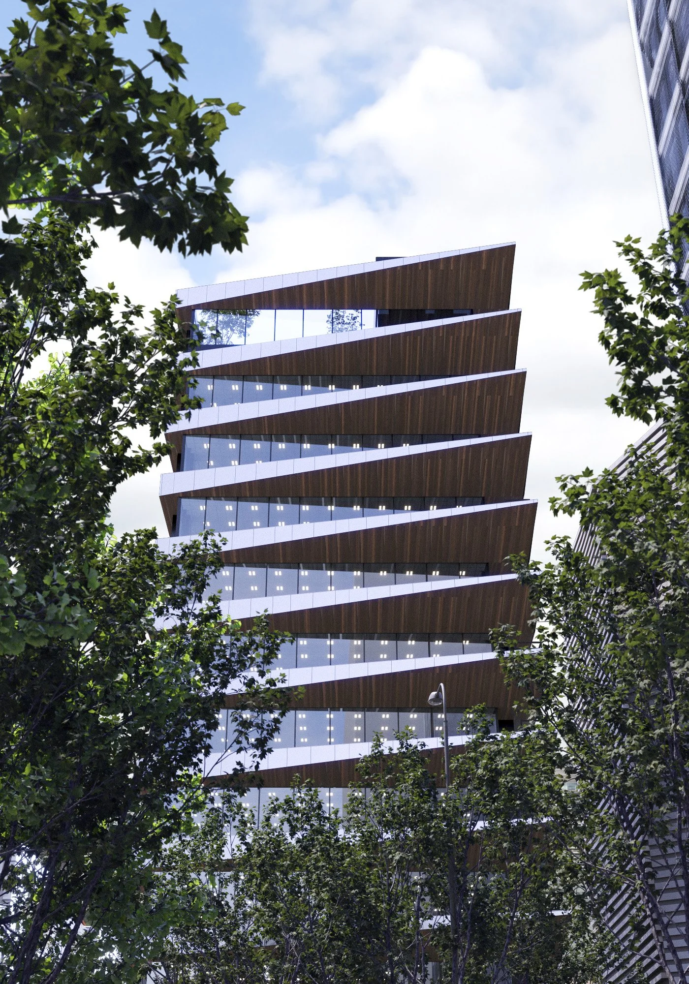 Modern multistory building with angular design, glass windows, surrounded by trees and a partly cloudy sky.