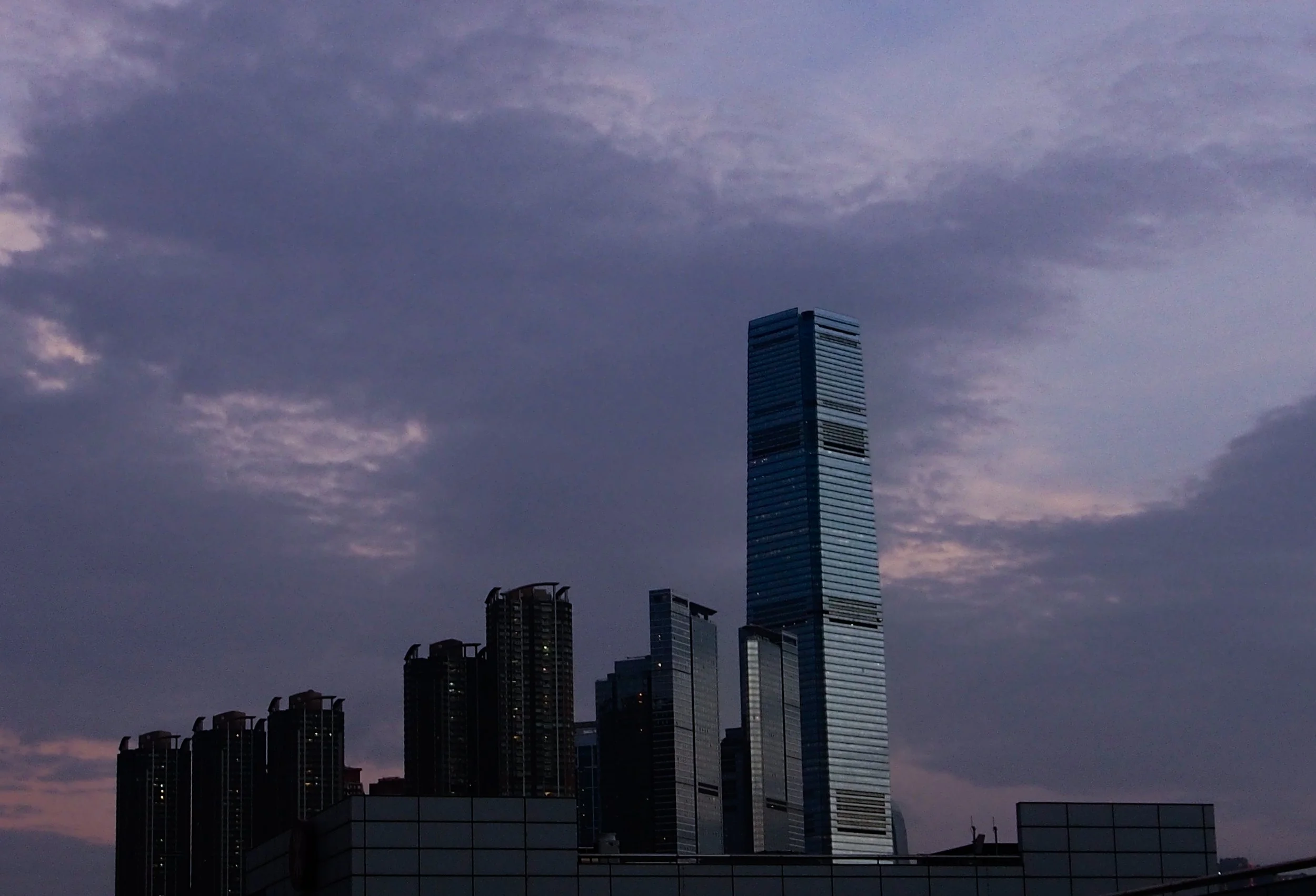 City skyline with tall skyscrapers and cloudy sky at dusk.