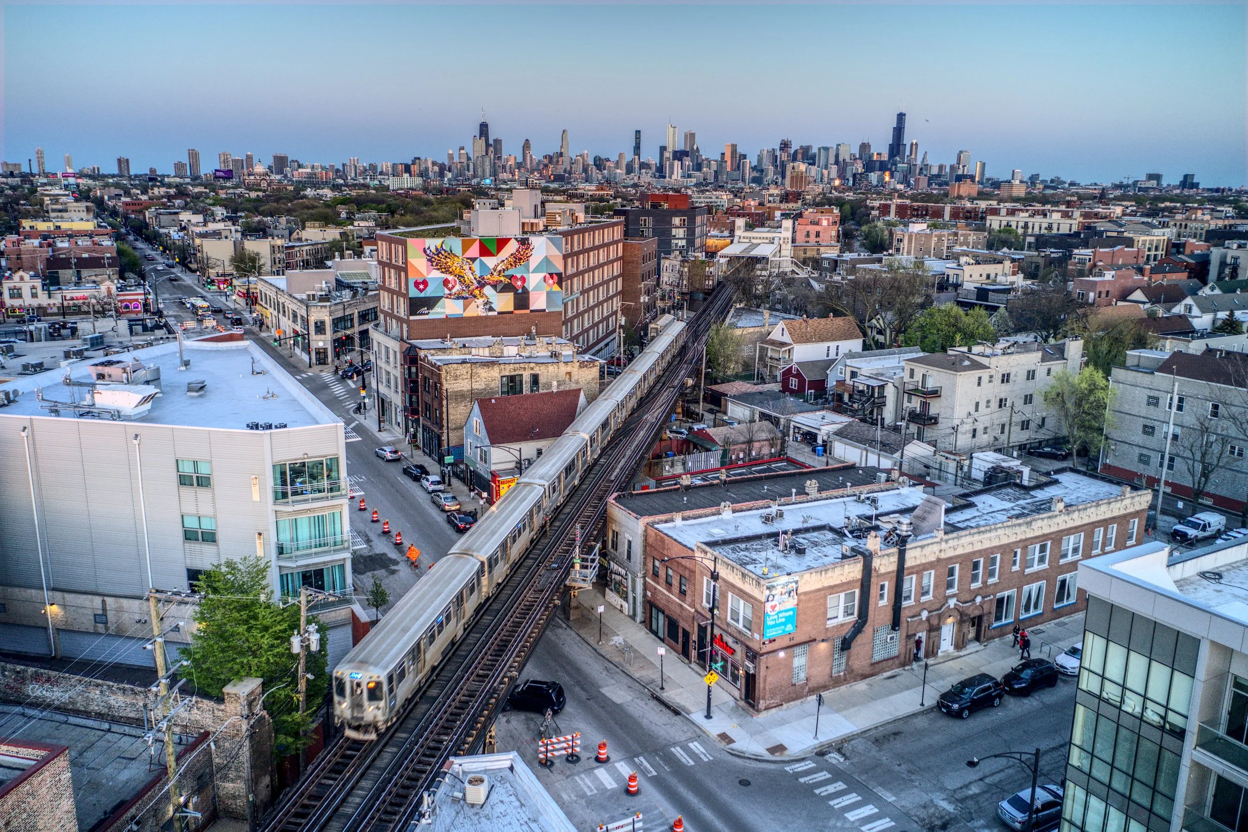 Aerial view of Chicago skyline with elevated train on tracks passing through city streets.