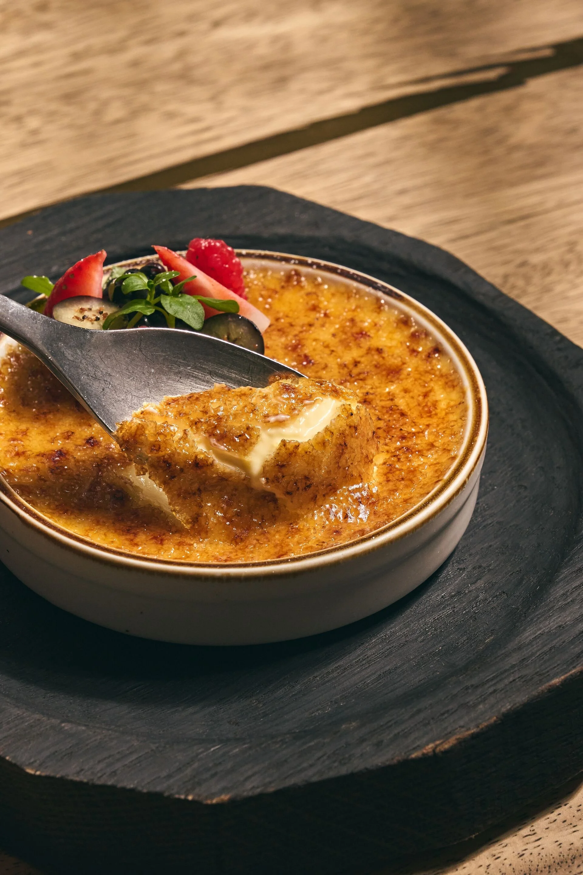 Crème brûlée garnished with fresh berries and microgreens.