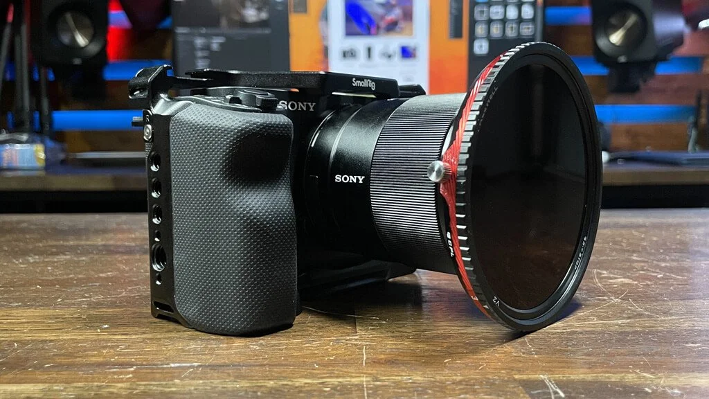 Camera with large lens on a wooden table in a tech shop or studio.