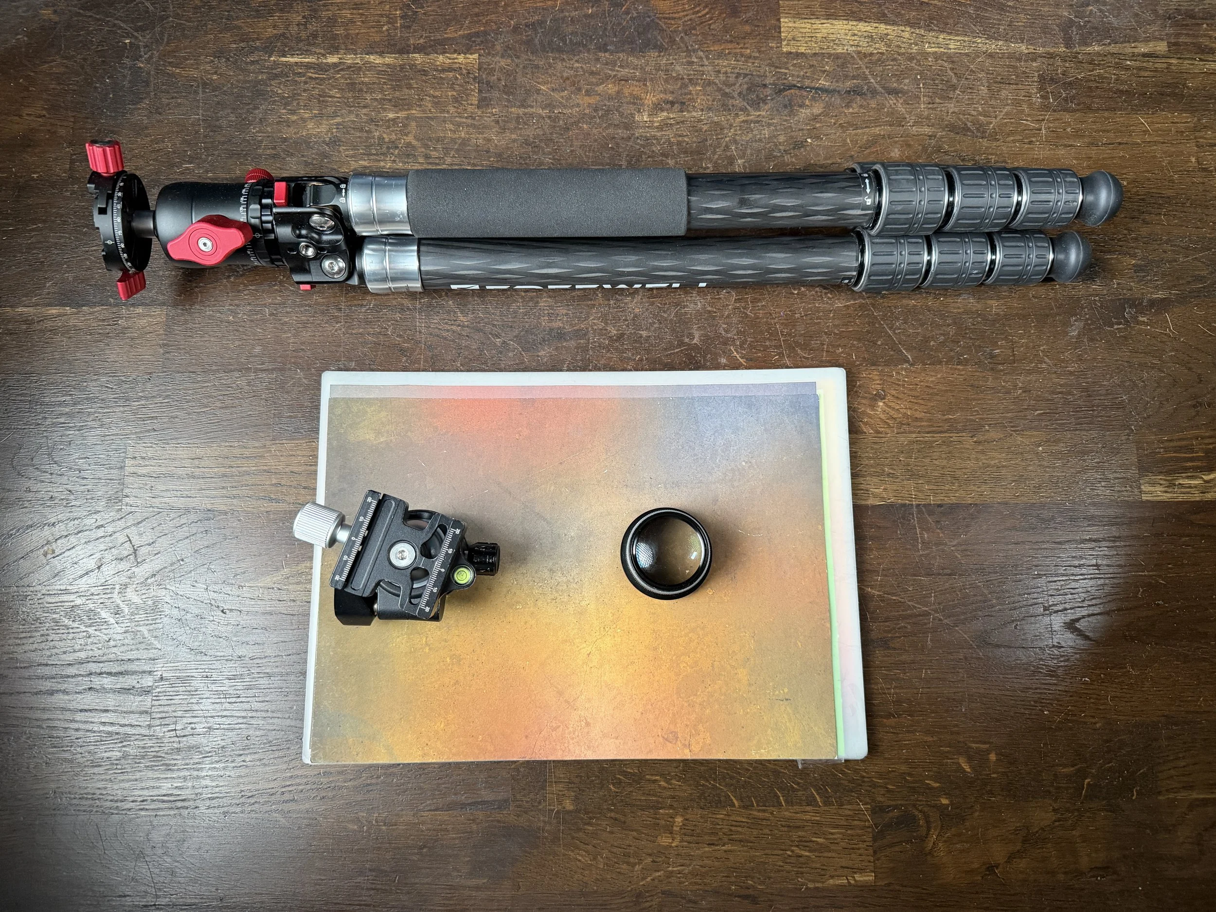 A professional camera tripod with two telescoping legs and a ball head on a wooden surface.