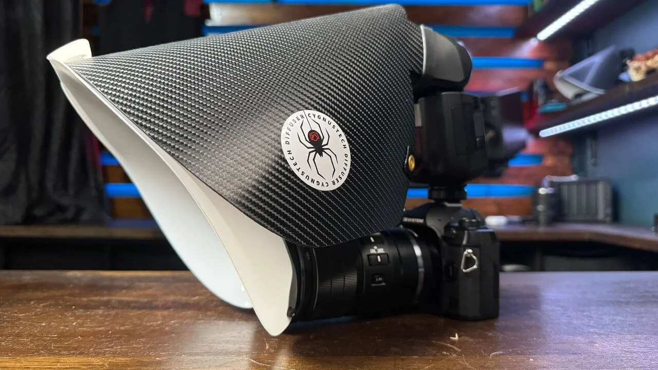 Close-up of a professional camera with a carbon fiber matte box and a spider logo sticker on it, placed on a wooden table.