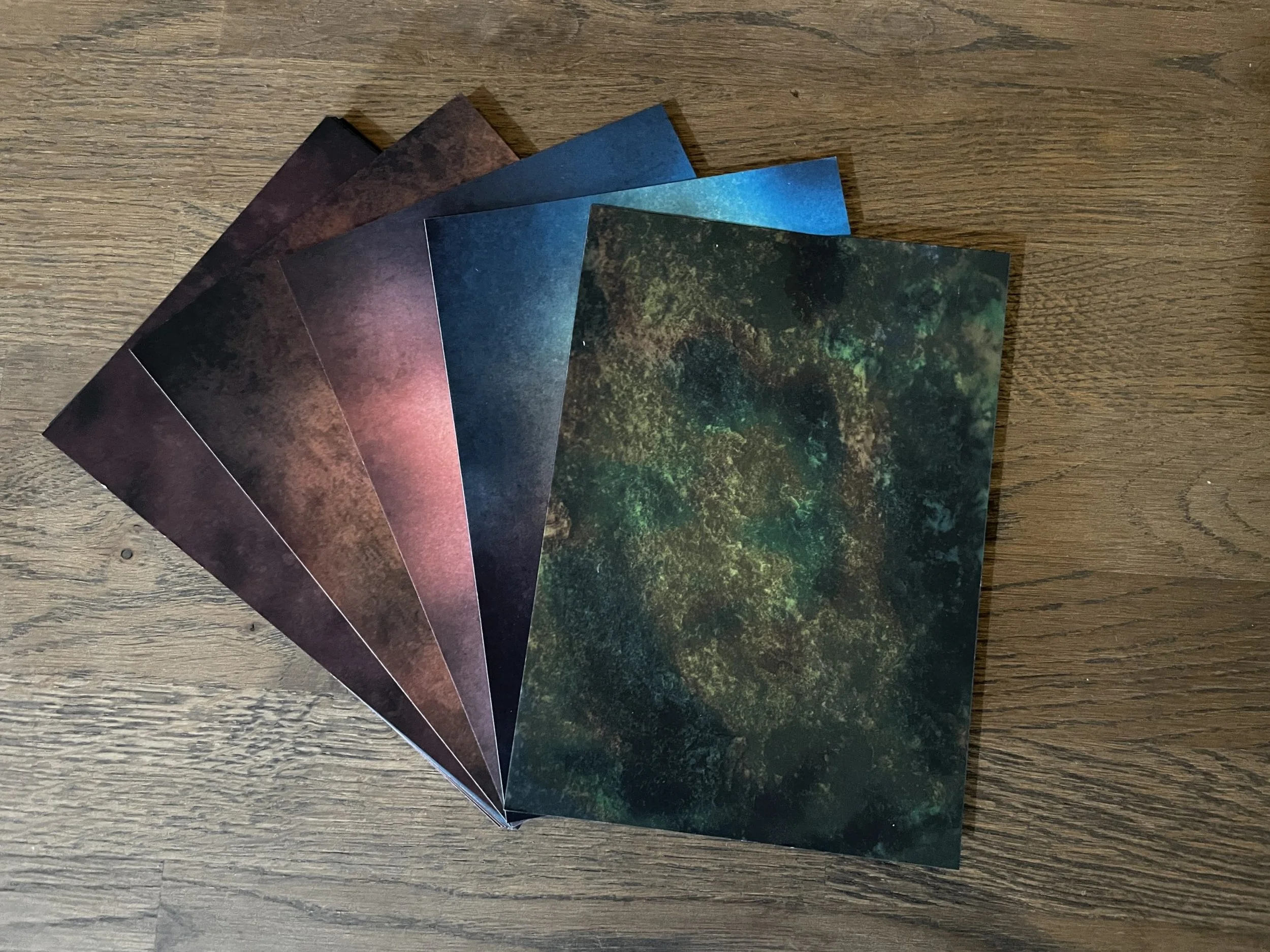 Six colorful postcards with space-themed images, fanned out on a wooden surface.