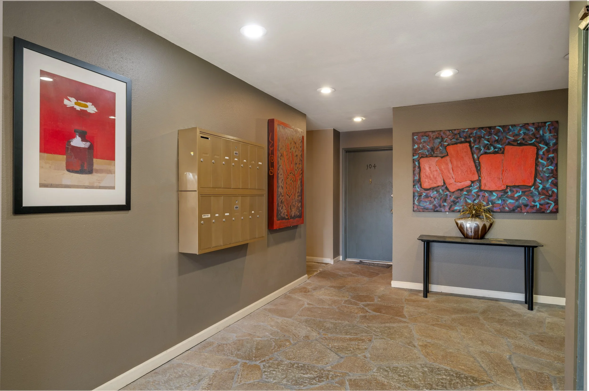 Apartment building lobby with artwork, mailboxes, and an entrance door.