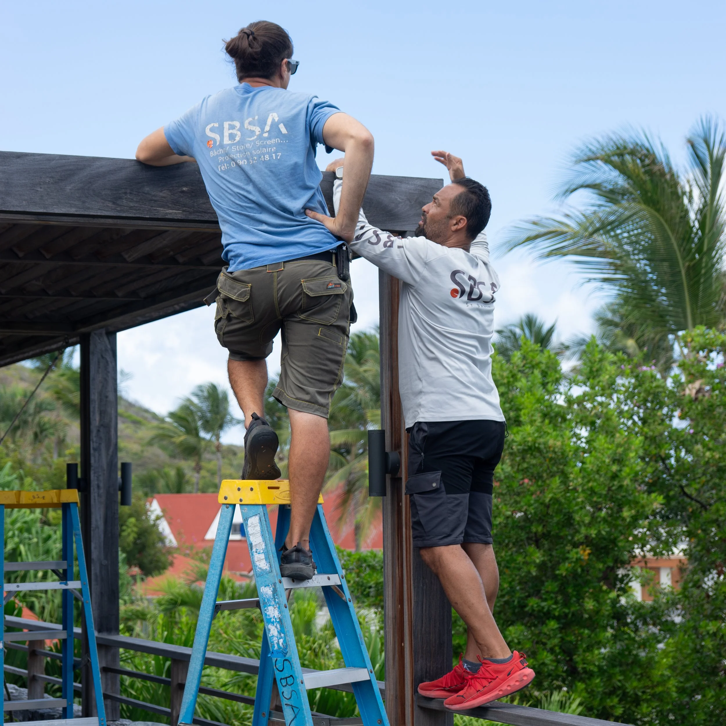 Two workers planning how to execute a installation of an awning for a luxury villa