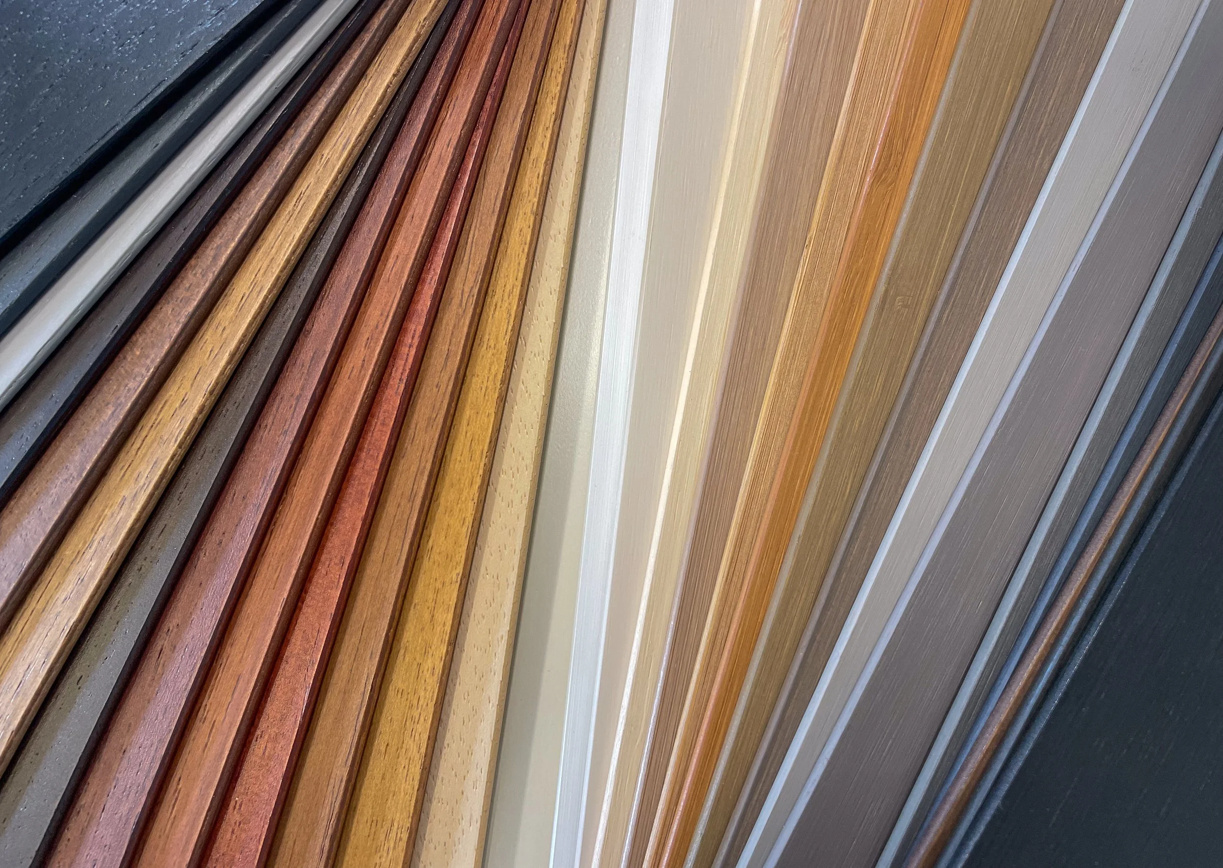 Une collection de lames en bois et en stratifié disposées côte à côte, présentant une variété de couleurs et de finitions.