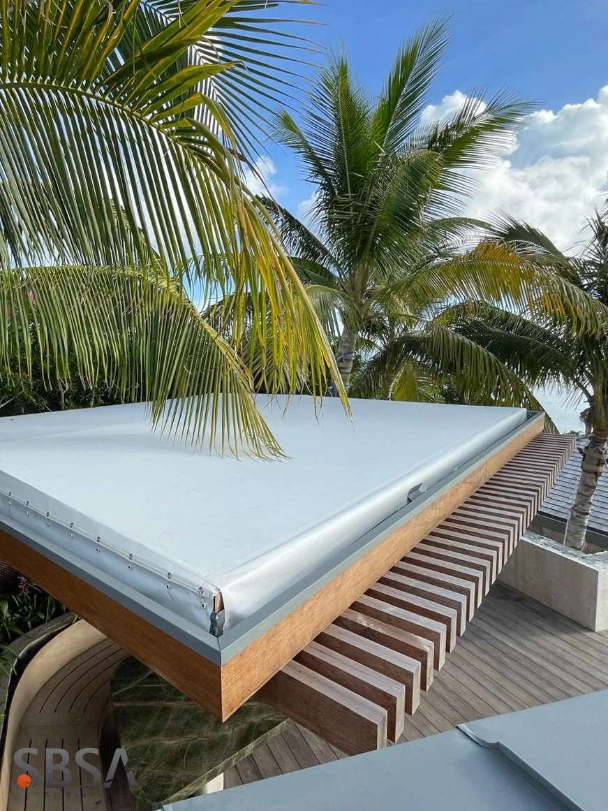 Outdoor patio with wooden decking and lounge chairs, surrounded by palm trees under a partly cloudy sky.