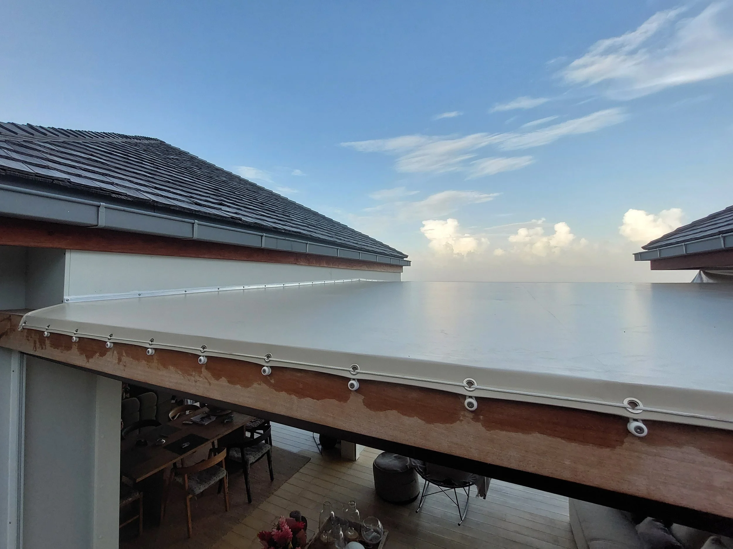 View of rooftops with shingle tiles against a blue sky with scattered clouds.