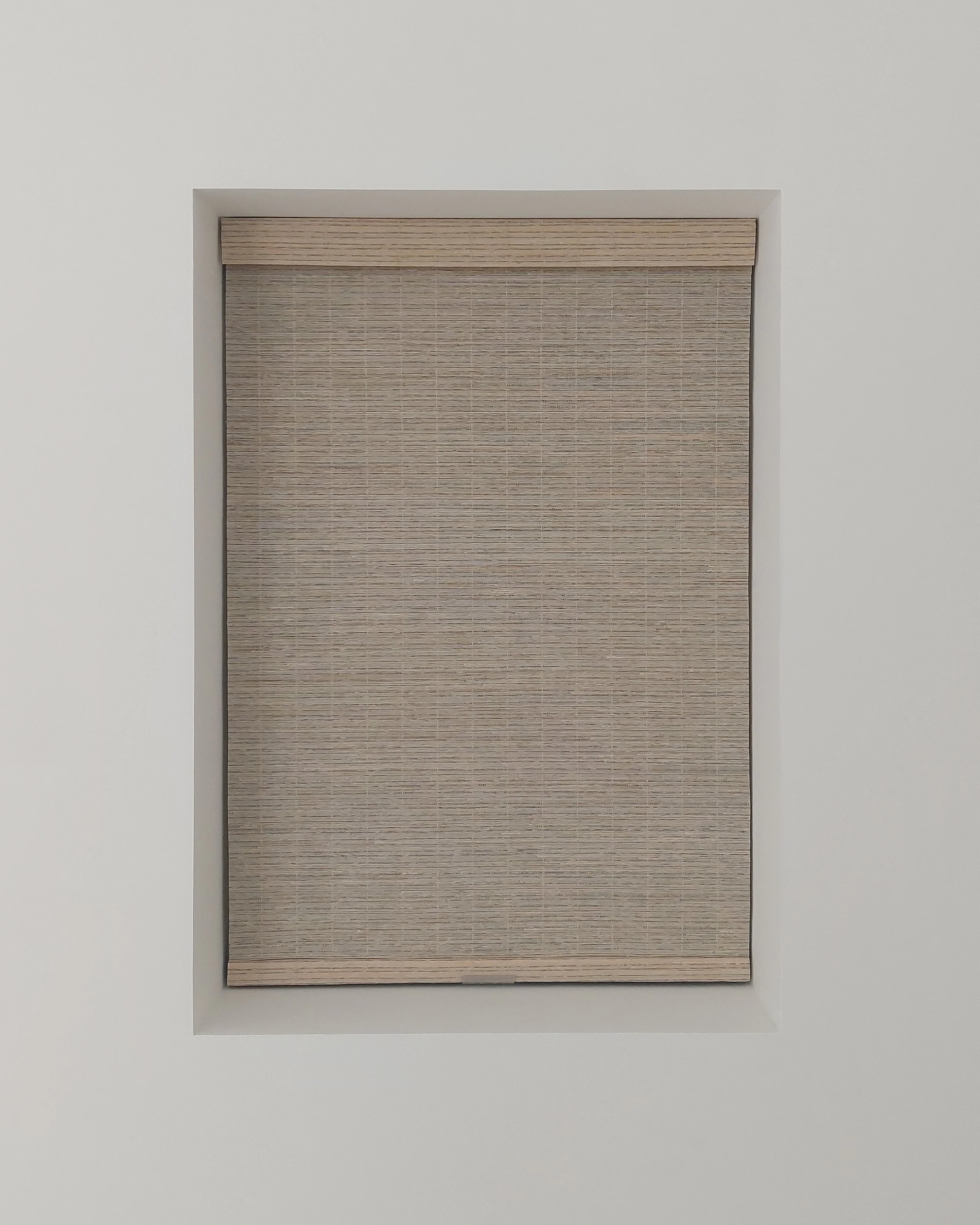 A wooden window shade partially rolled up in a white wall niche.