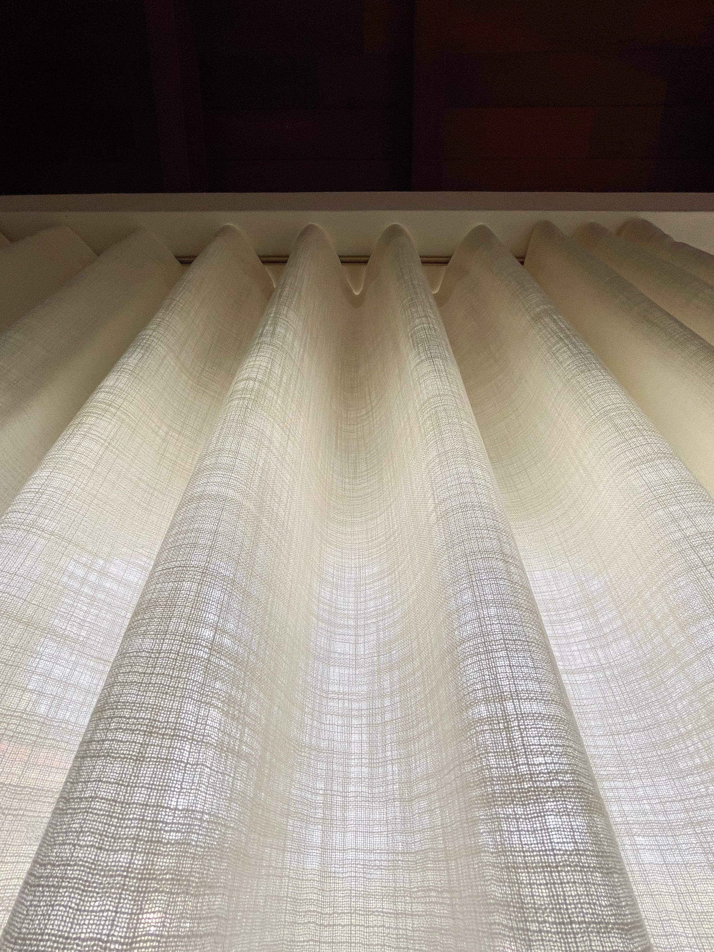 Une fine et transparente rideau blanc en lin ou en coton, suspendu devant une fenêtre, laissant passer la lumière du jour.