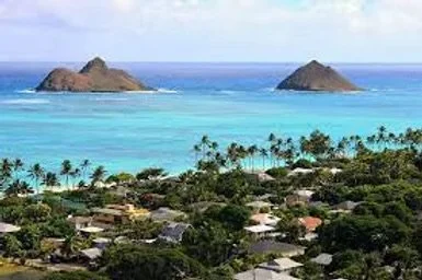 A tropical coastal scene with turquoise waters, two small islands, and a lush green shoreline with houses and palm trees.