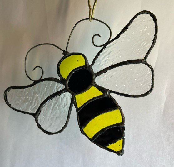 Decorative sun catcher of a bee with white wings and yellow and black striped body.