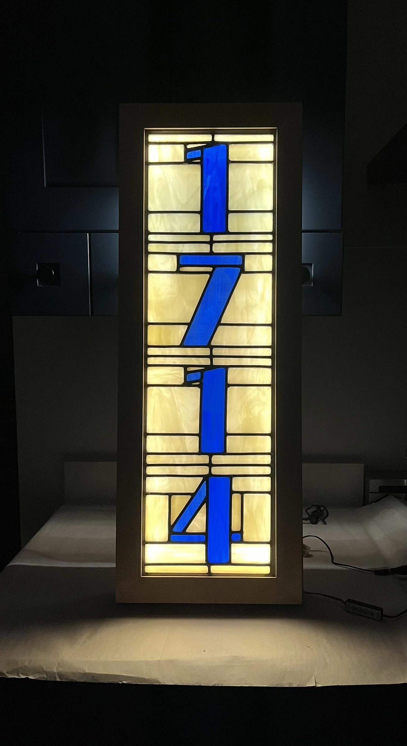 A stained glass street address panel with the numbers 1, 7, 1, 4 in blue on a yellow and cream background.