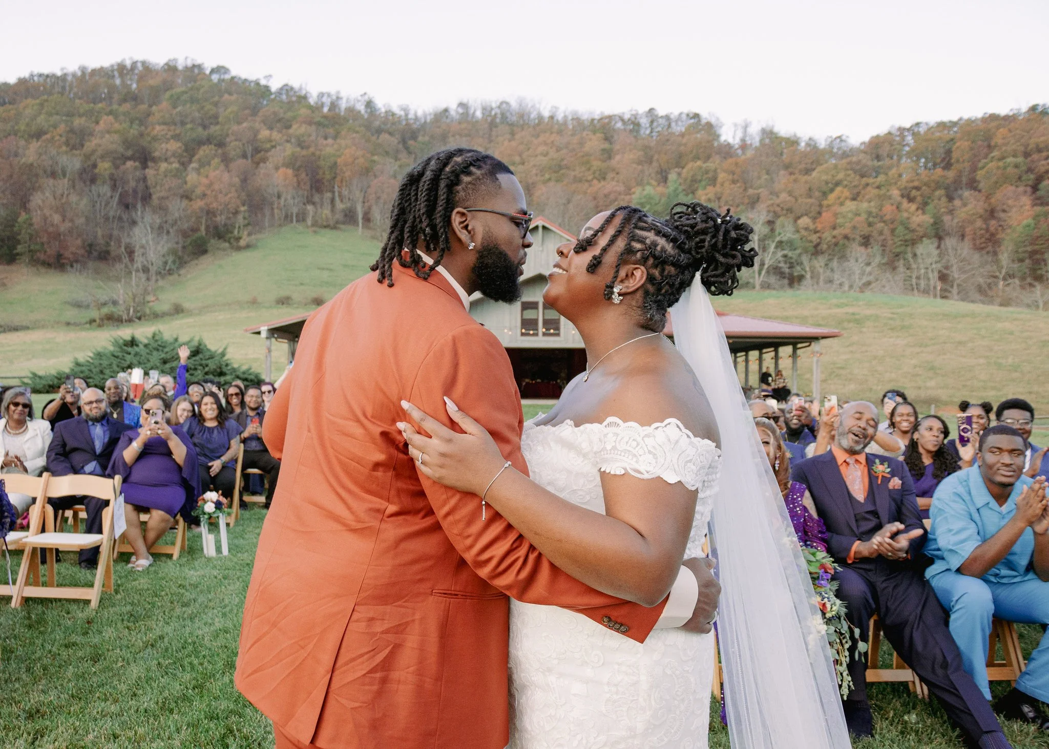 Scenic landscape of a calm lake surrounded by rolling hills and mountains under cloudy sky
