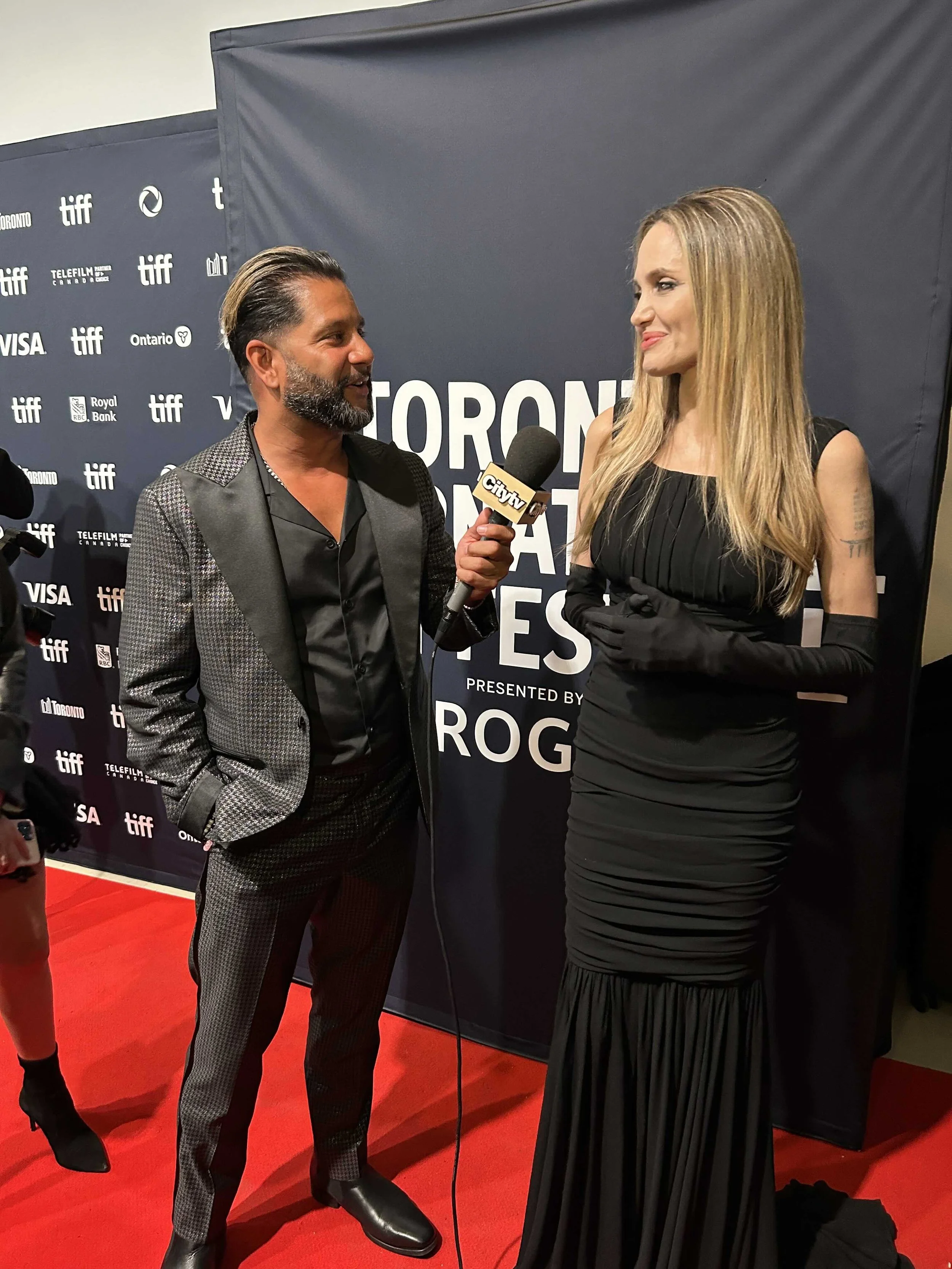 Devo Brown conducting a red carpet interview at a live event with Angelina Jolie
