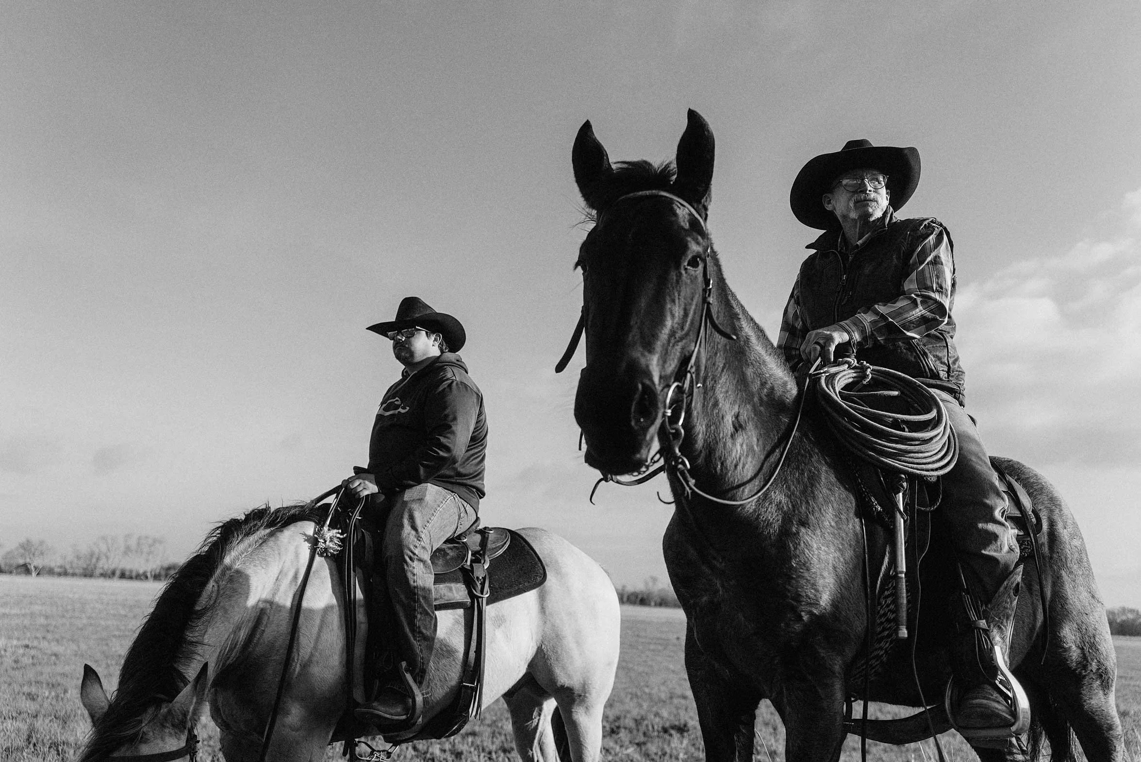 two cowboys on horseback posing side by side black and white