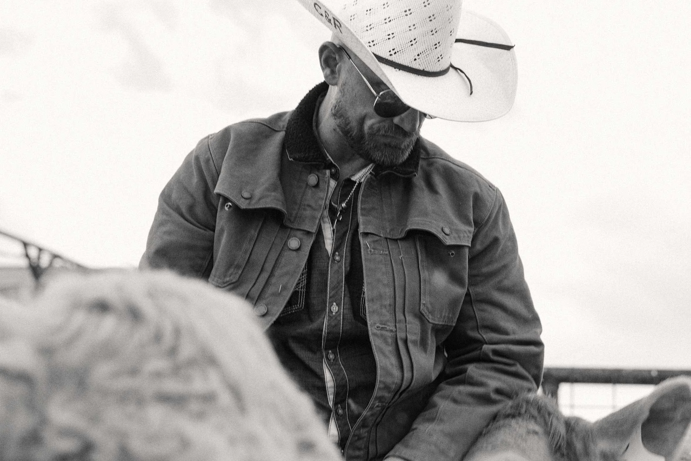 black and white portrait of a cowboy sitting and looking down