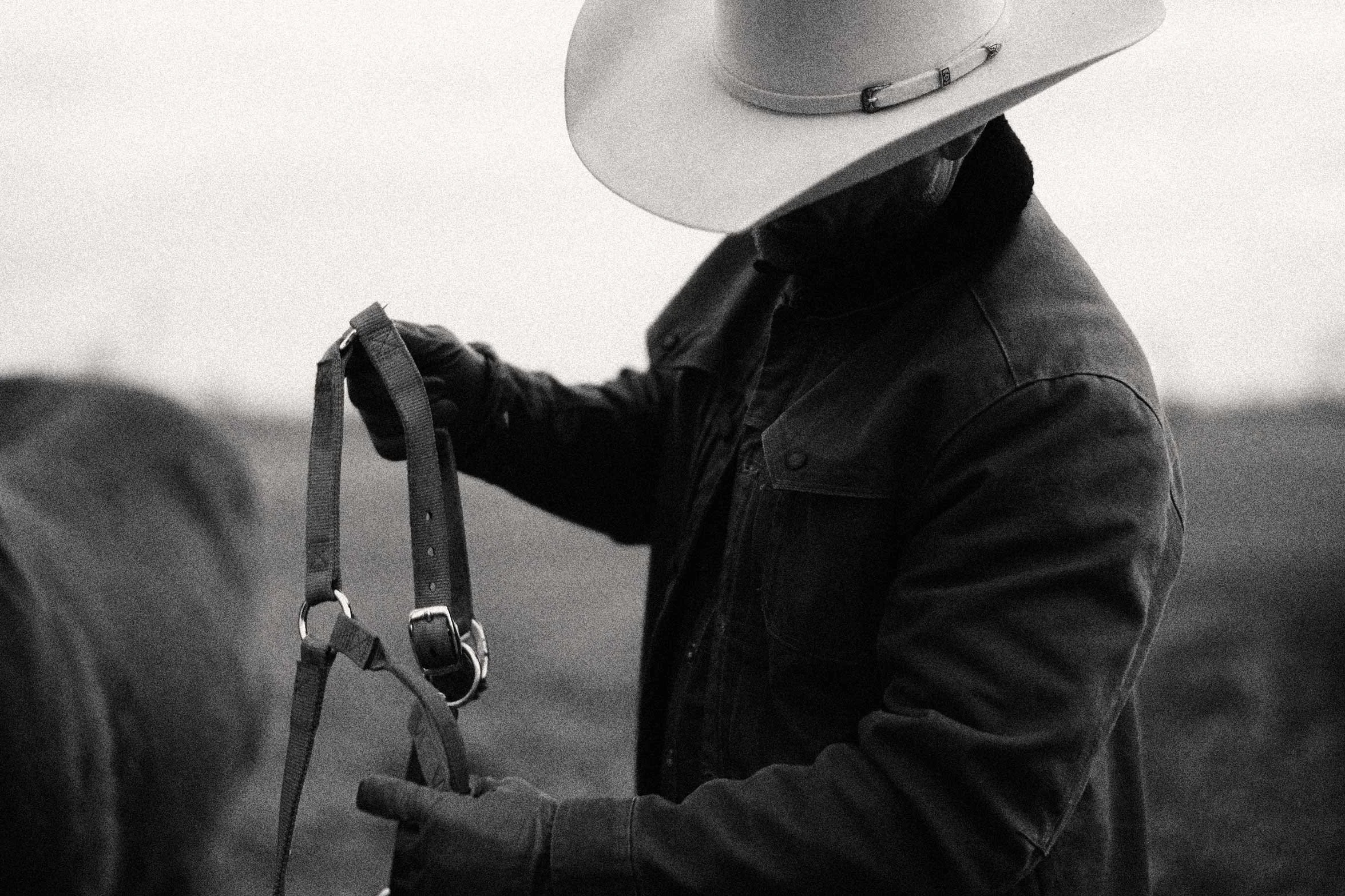 cowboy holding horse reins close up black and white