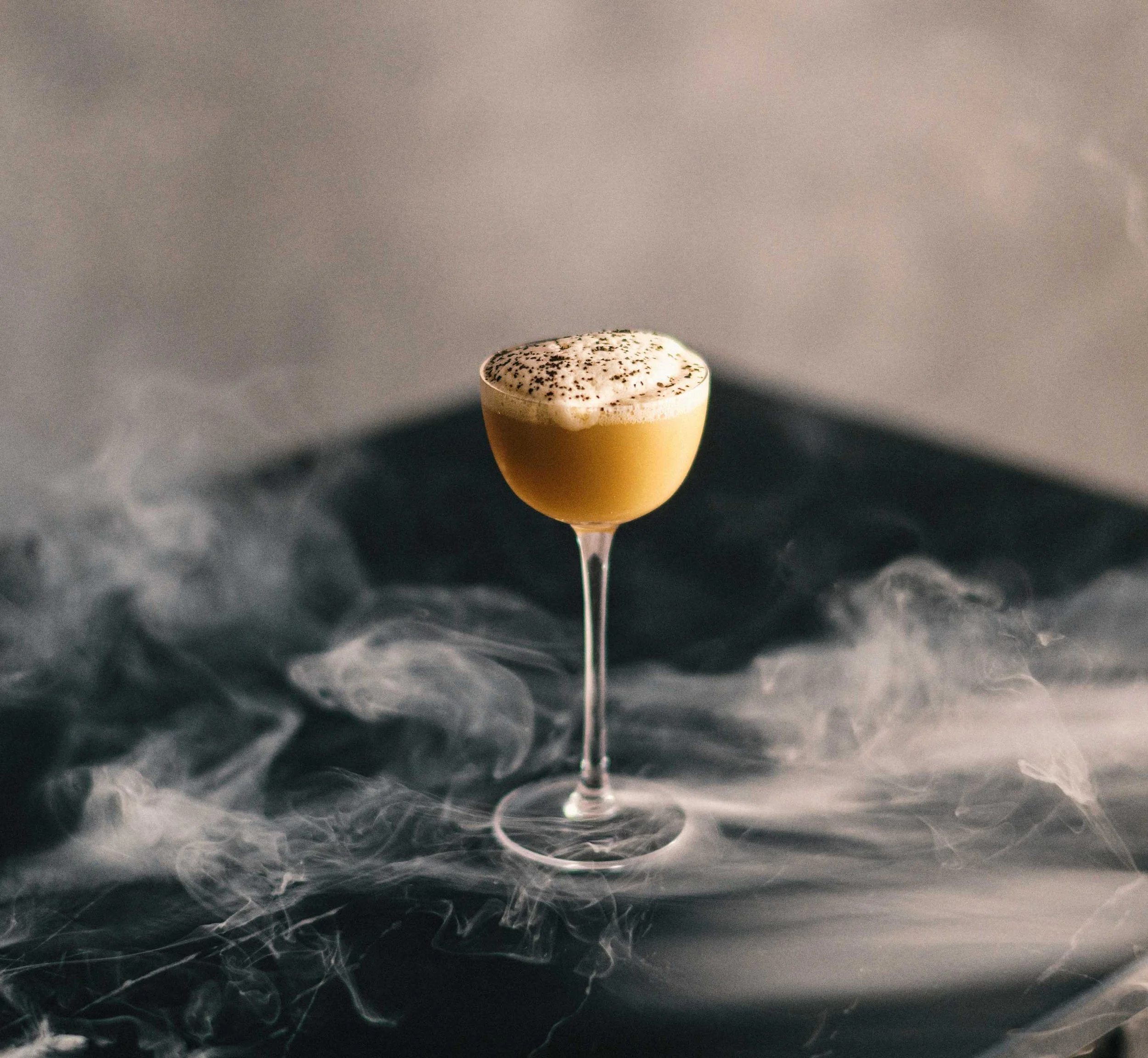 espresso martini in a coupe glass surrounded by low fog or smoke