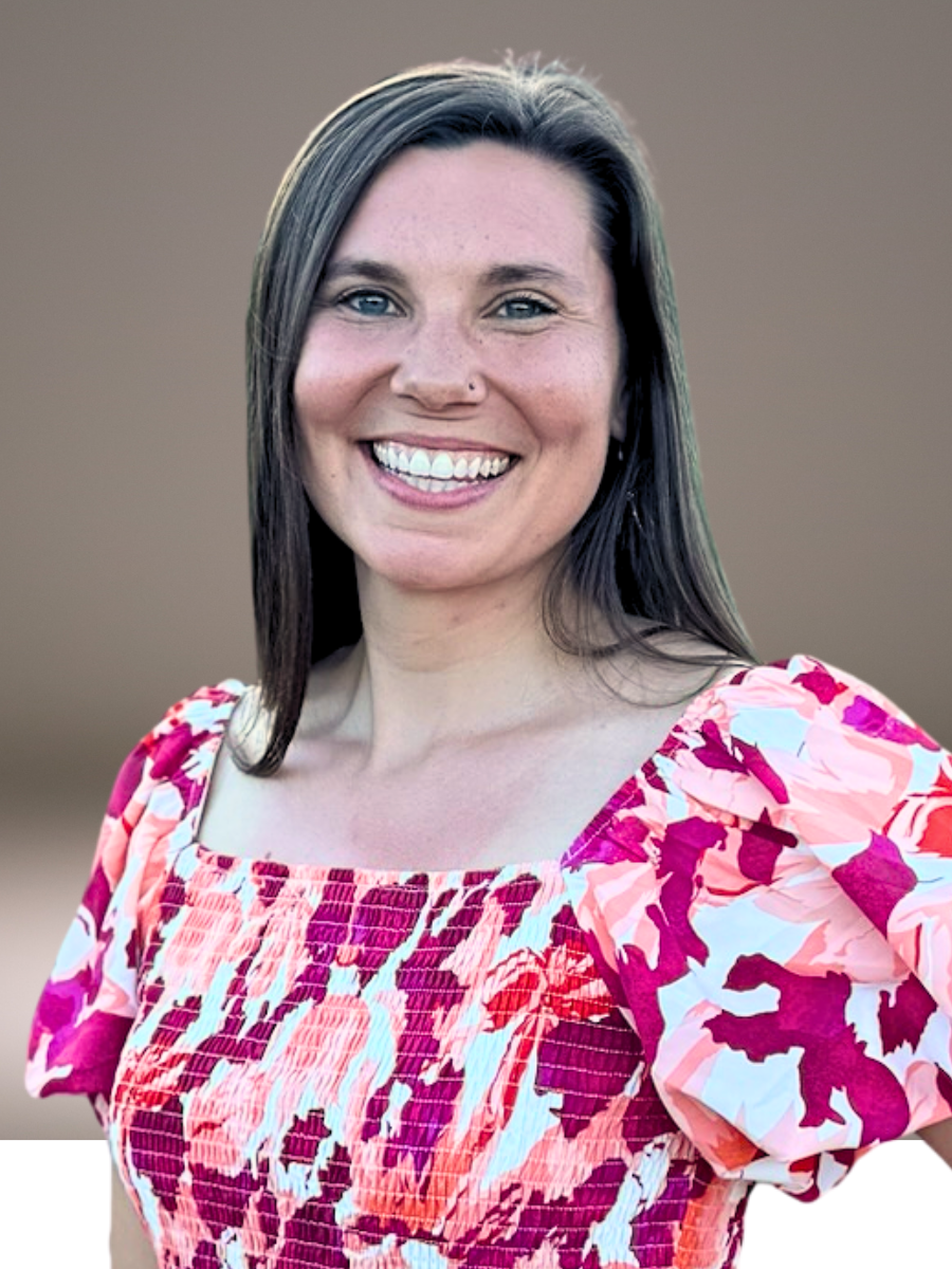 A woman with long dark hair, fair skin, and a nose piercing, smiling at the camera, wearing a pink and red patterned dress. She volunteers at Grace Capital City, a church in Washington, DC.