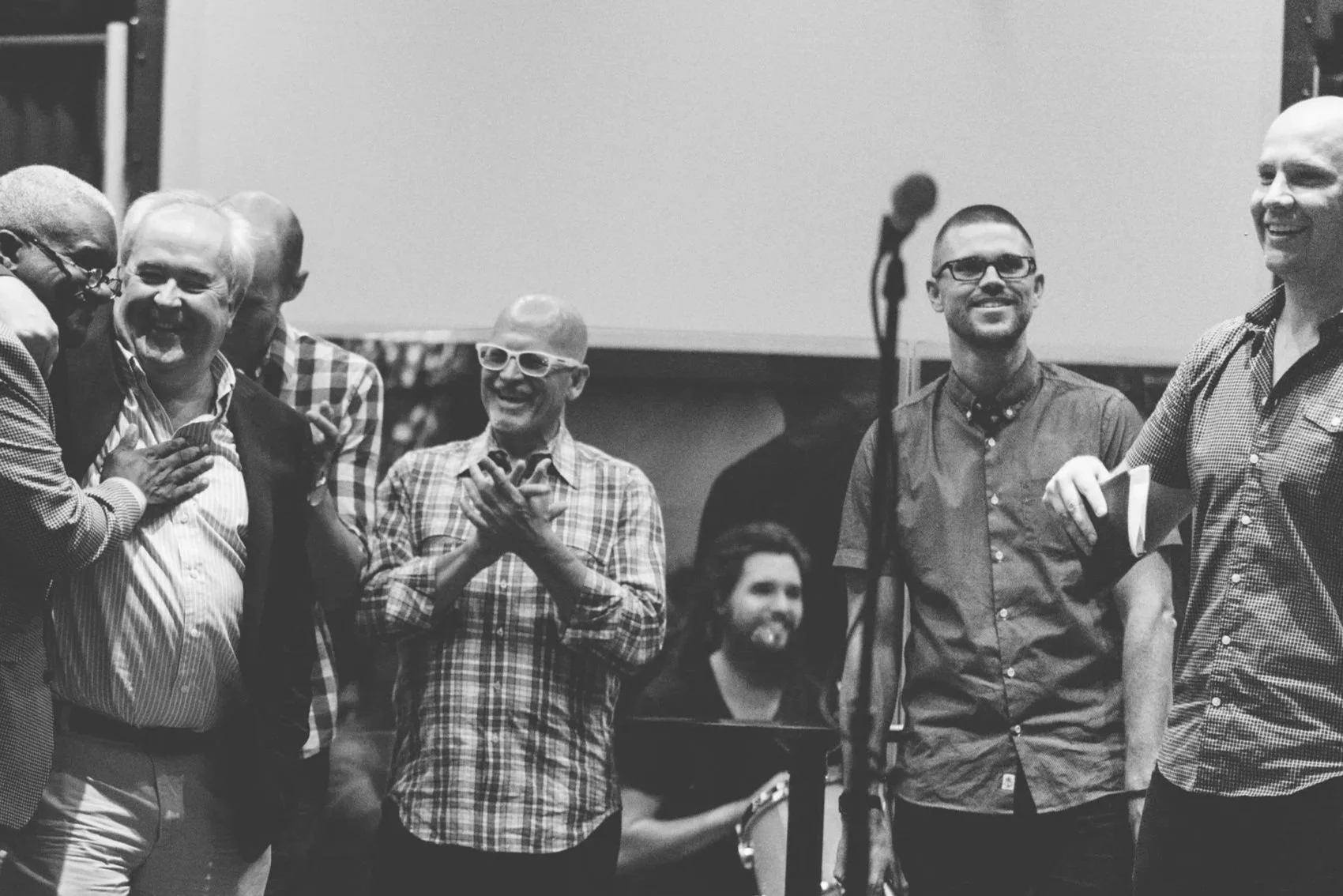 Group of men smiling and laughing together, some wearing glasses, at a church service launching the founders of Grace Capital City, a church in Washington, DC.
