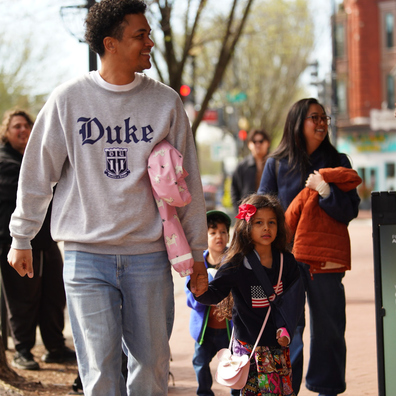 A smiling dad holding his young daughter's hand and a smiling mom holding her young son's hand walk into Grace Capital City, their church that meets at a theater in Washington, DC.