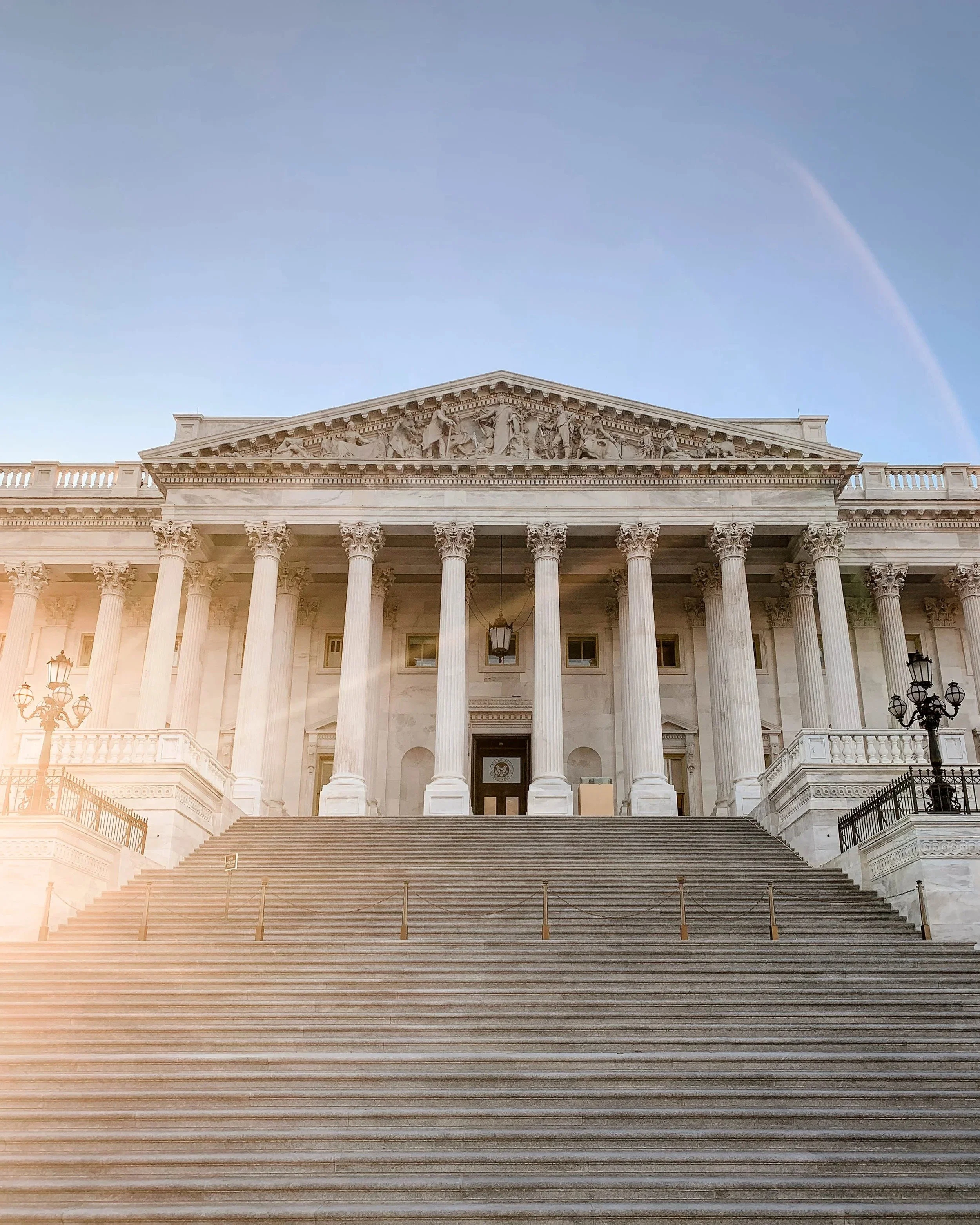 The United States Capitol building in Washington, DC where Grace Capital City, a church, meets. There are grand steps, tall columns, and detailed sculptures, illuminated by soft lighting with a clear sky in the background.