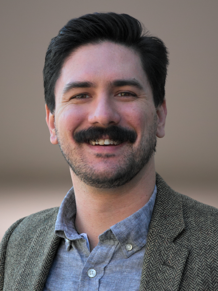 A white man with dark hair, a beard, and mustache smiling outdoors. He volunteers at Grace Capital City, a church in Washington, DC.